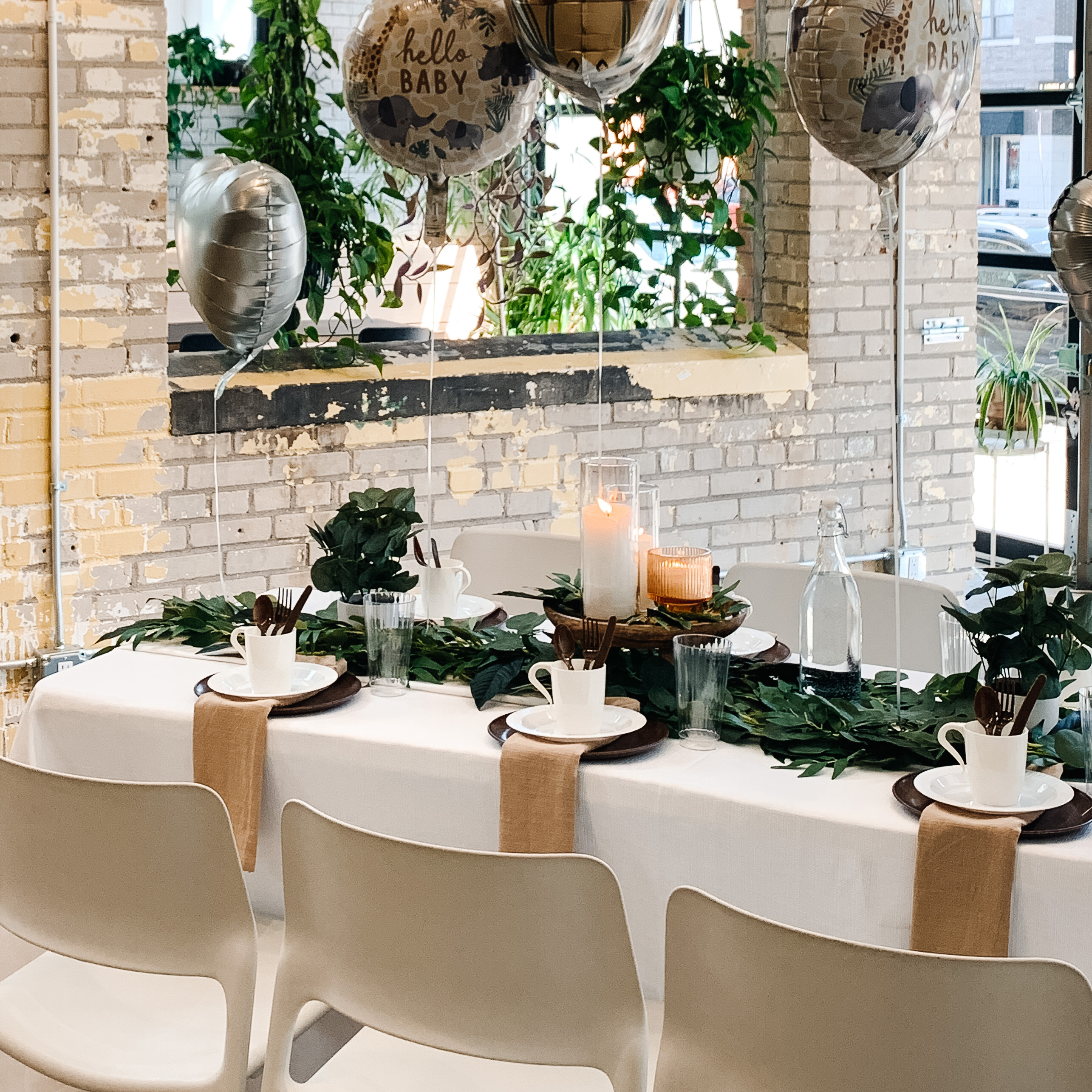 Tablescape with candles, greenery, balloons, plates, and mugs