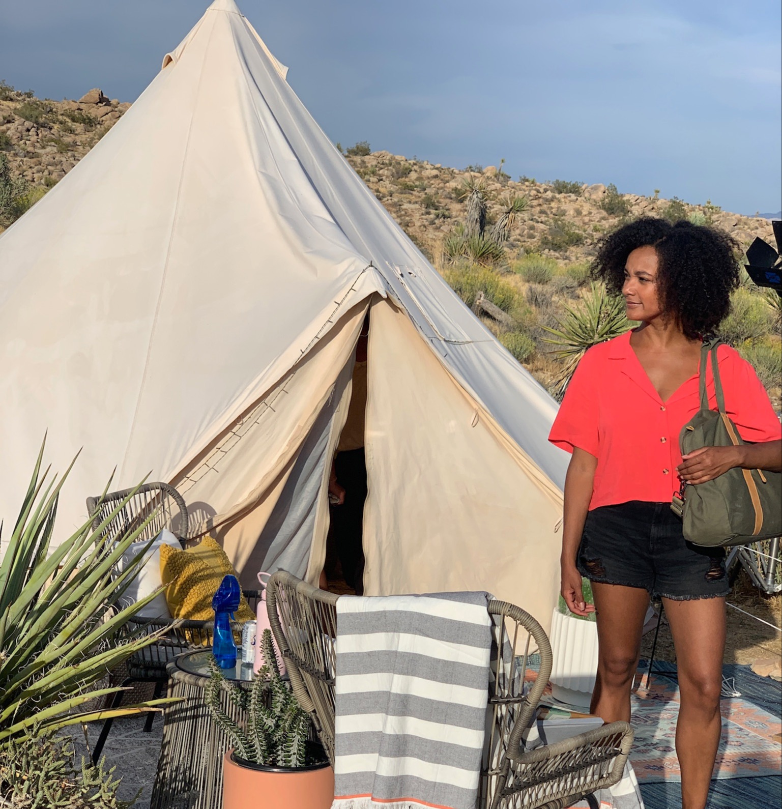 Black woman standing in her swimsuit at a desert glamping campsite with a steel basin for a pool