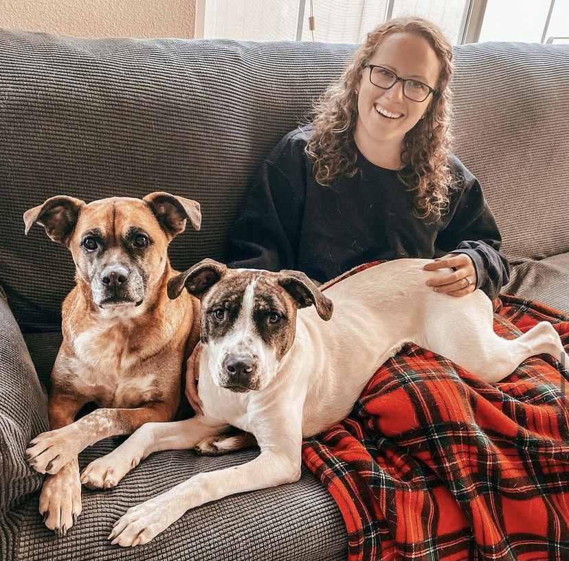 an image of a young woman and her two large dogs sitting got a couch