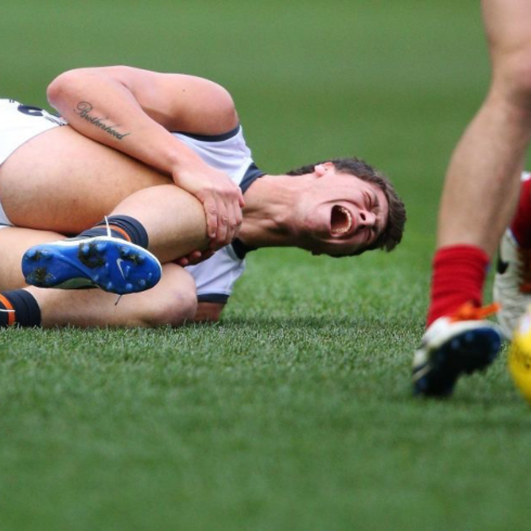 Young AFL athlete in pain from ACL tear.