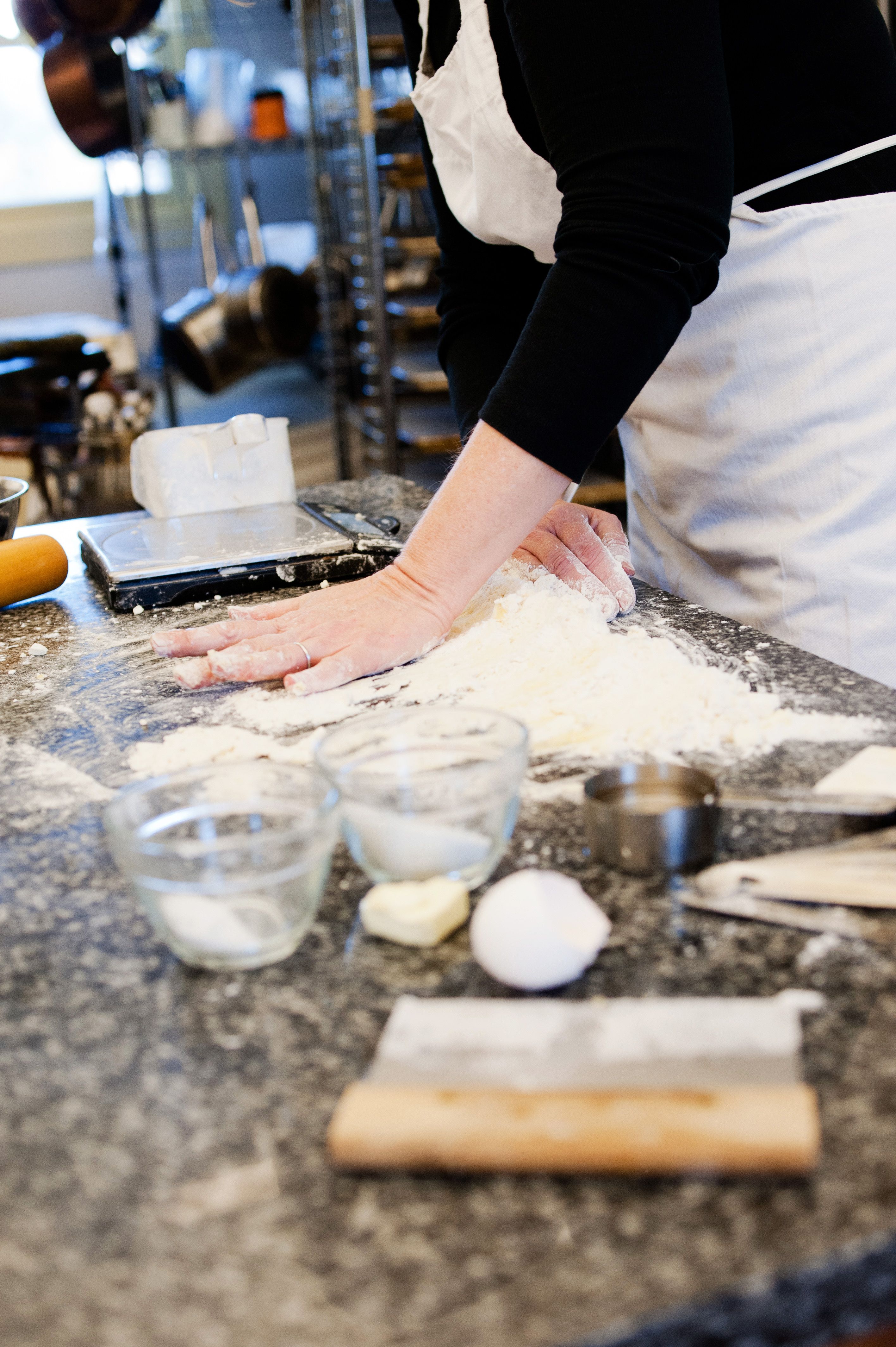 Susan is kneading dough mixture on a granite countertop.