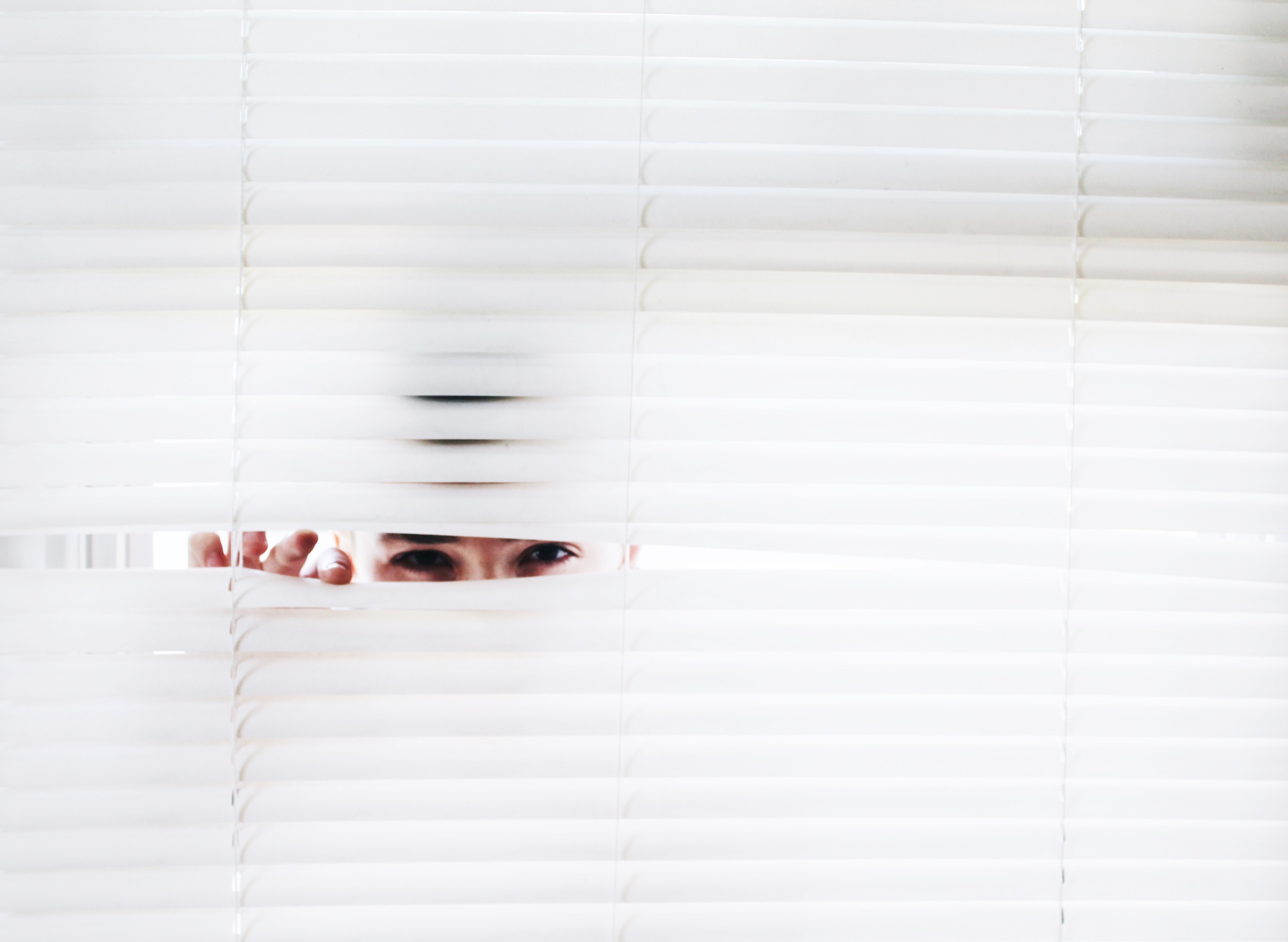 person peeking through blinds