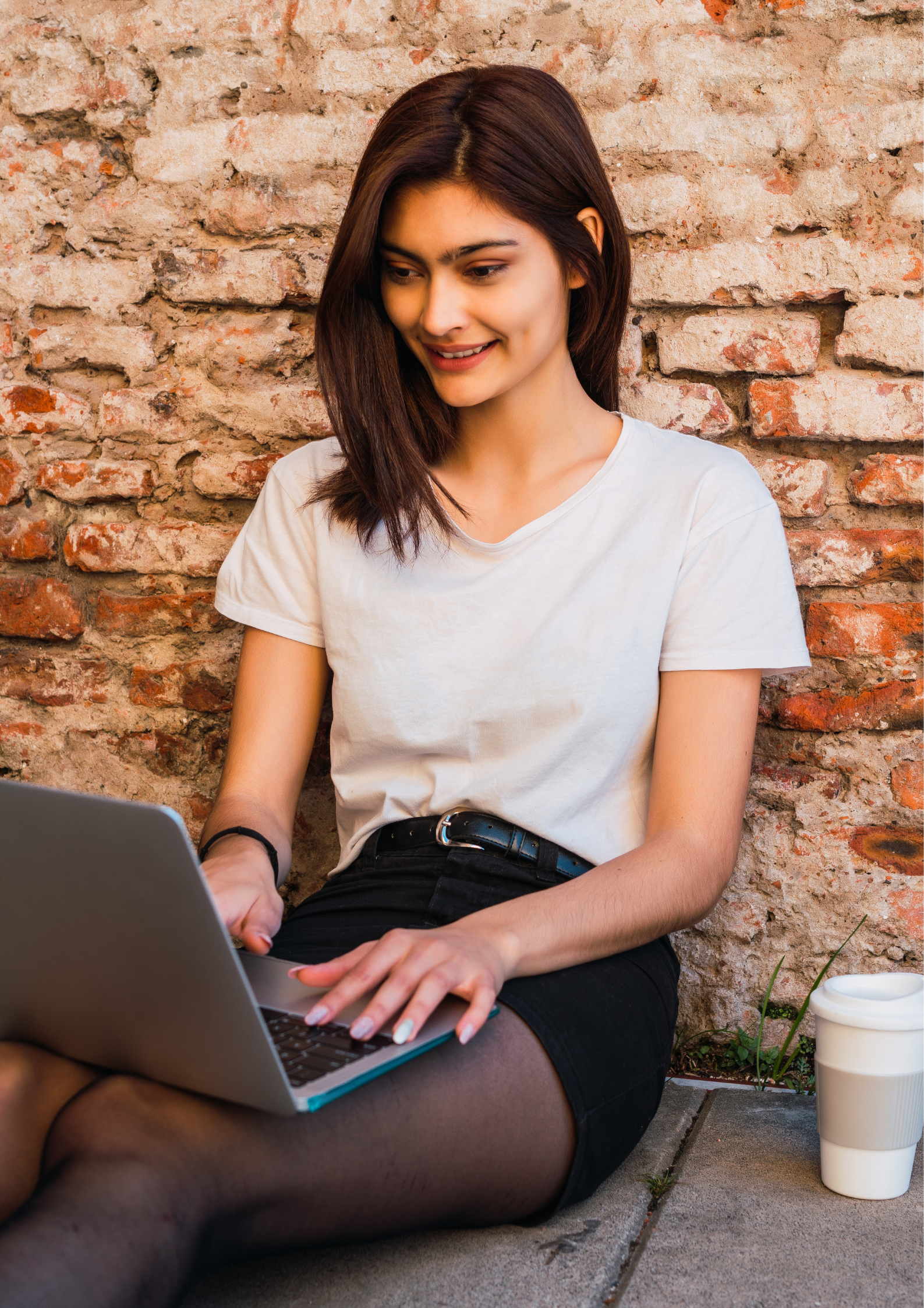 Researcher sat by a wall on their laptop