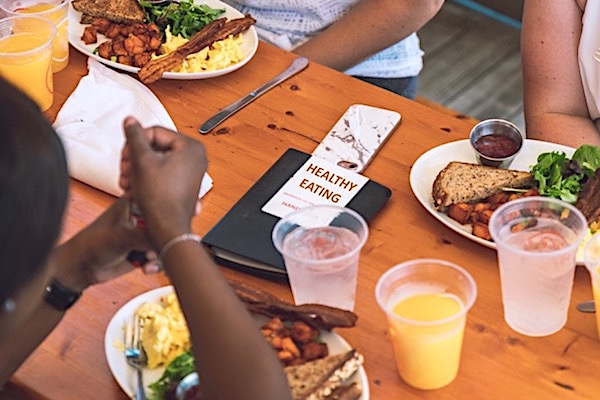 People eating at a table with a pamphlet in the middle with text that says 