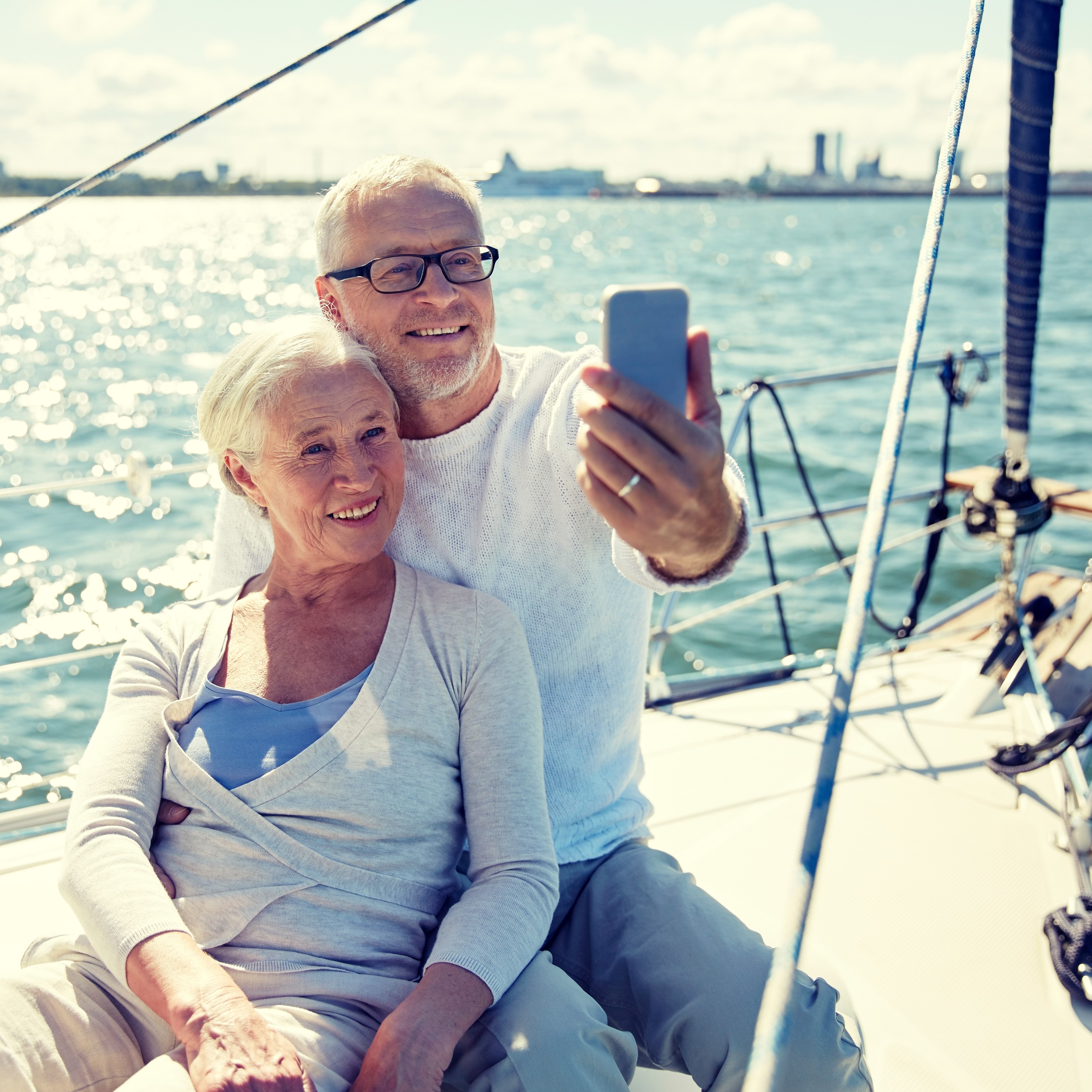 Retired couple on a boat, taking a selfie on the water with a skyline in the background