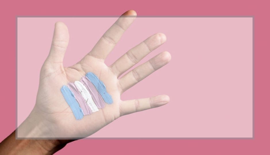 Palm of hand on pink background. Blue/pink/white trans color paints are across palm. 
