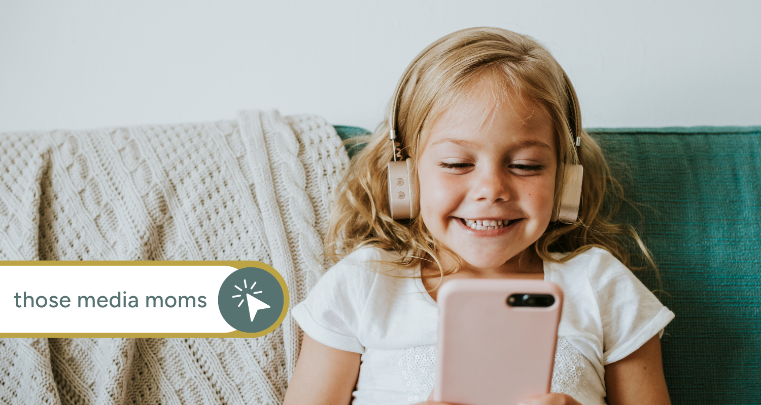 Preschool-aged child holding a smart phone and wearing headphones