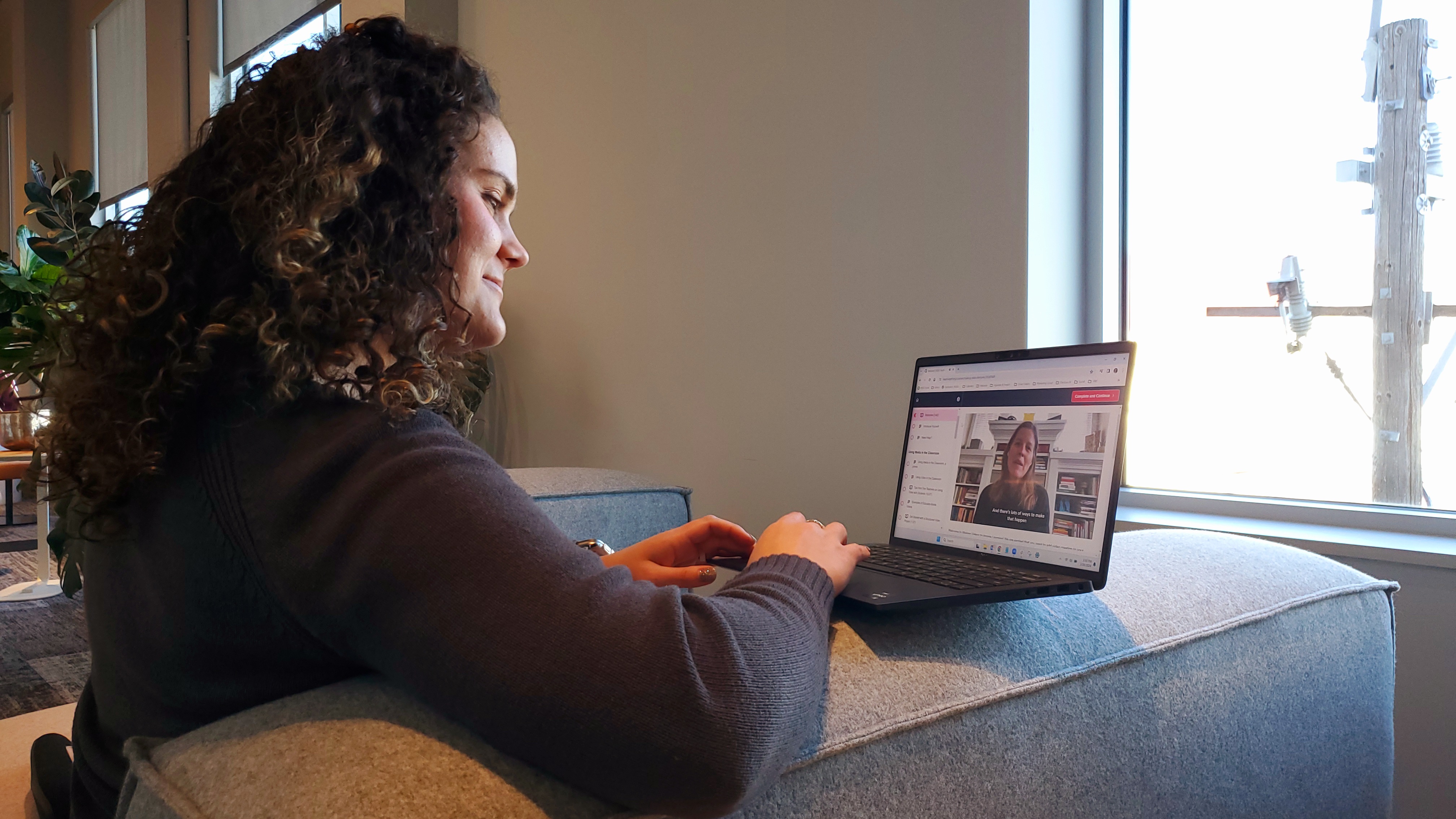 Woman sits on a couch working on her laptop