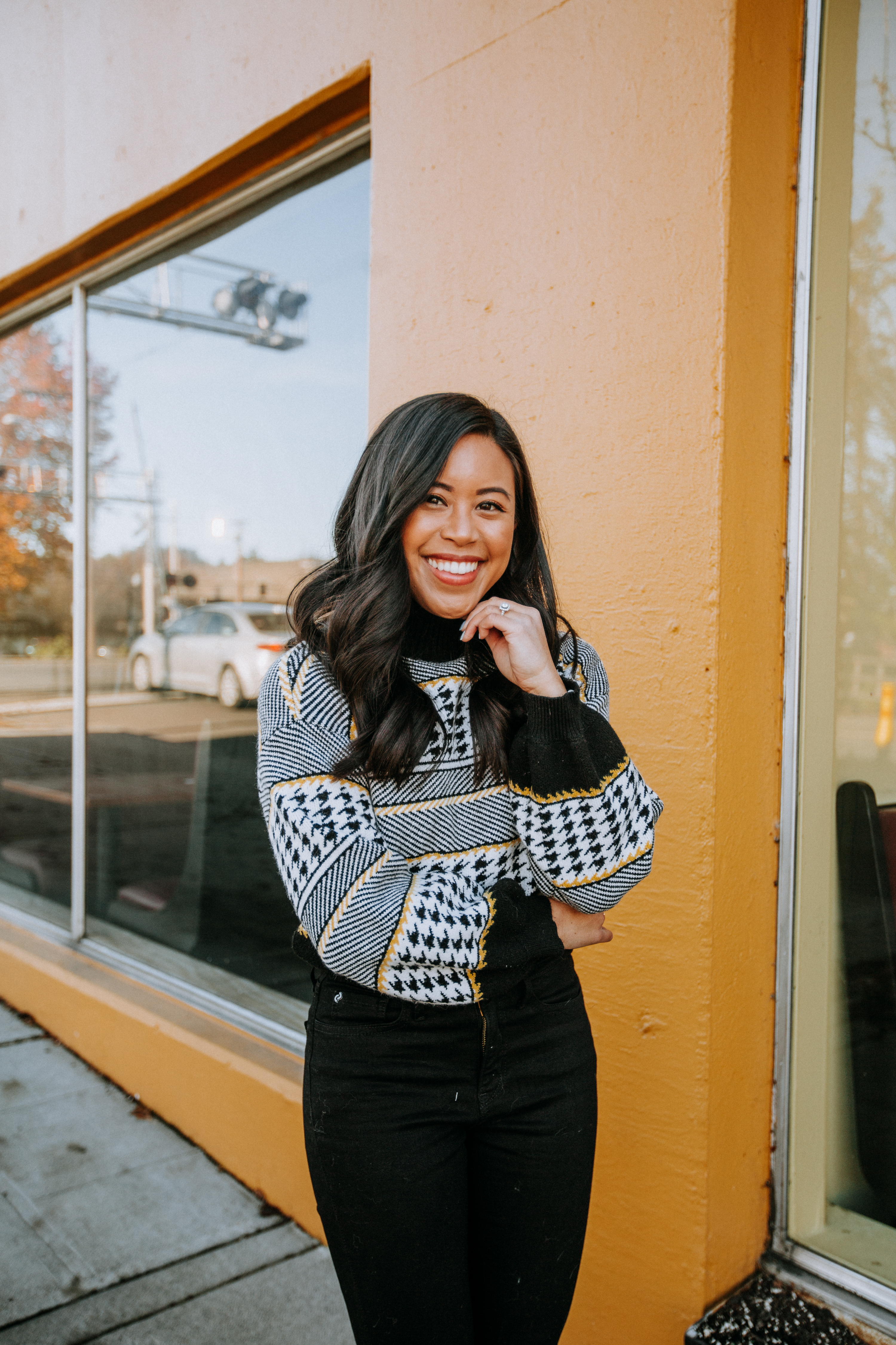 Wearing a houndstooth sweater in front of a yellow wall