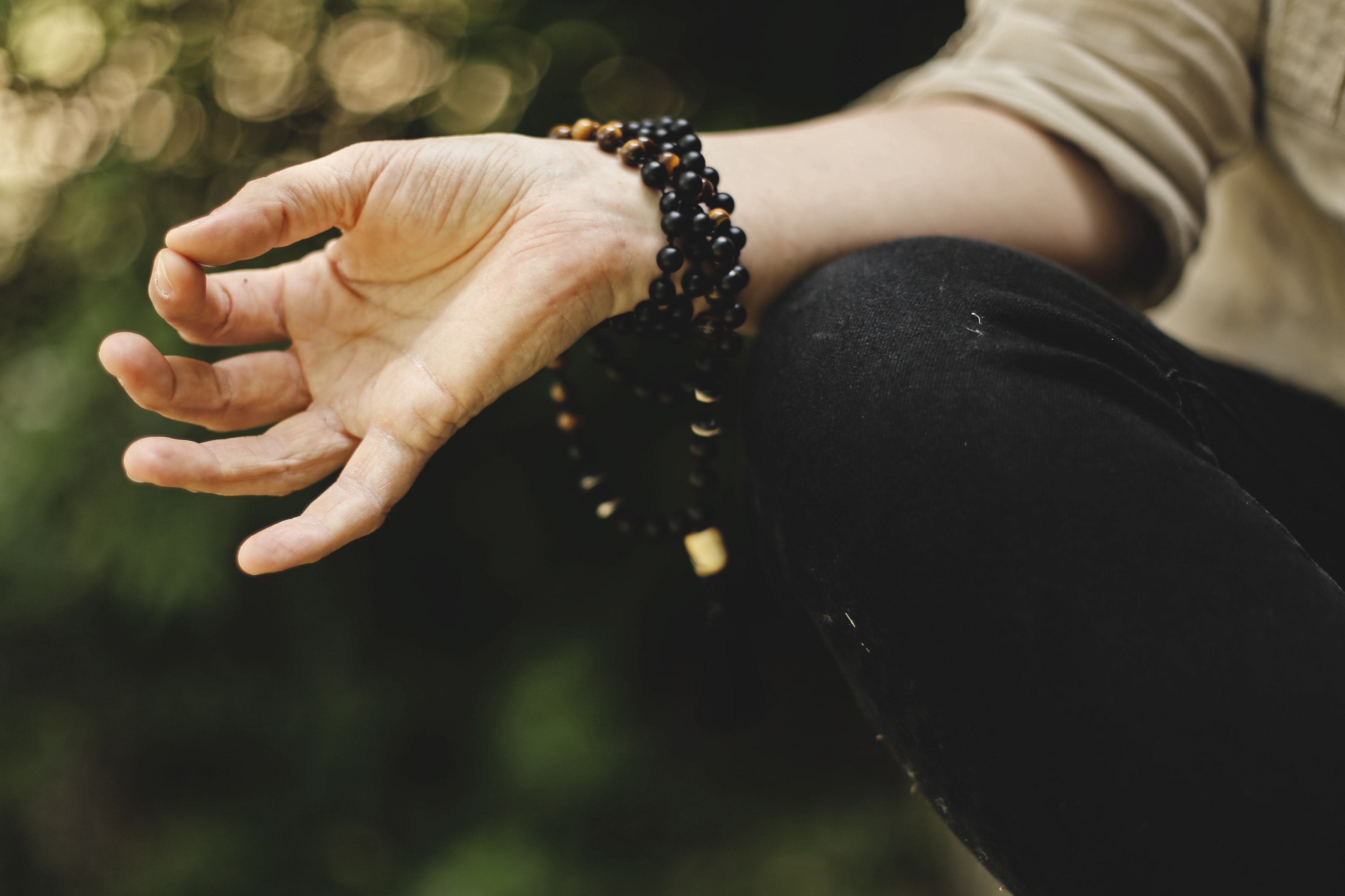Hand in yoga mudra wearing mandala beads