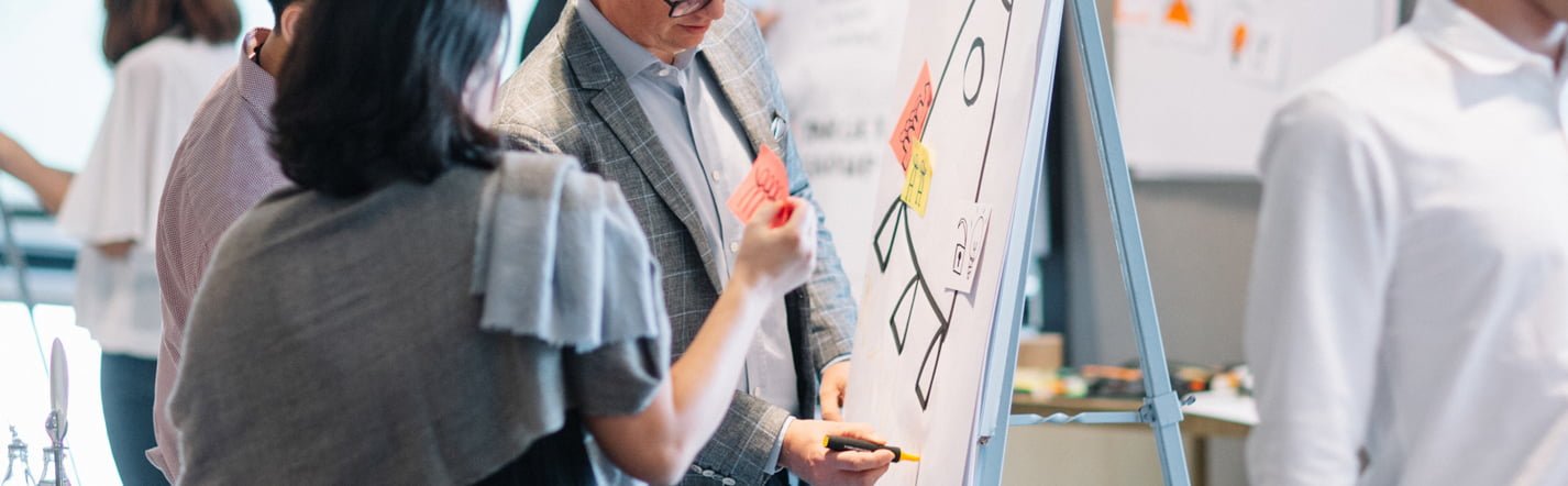 Photo of a man and woman drawing on a flipchart.