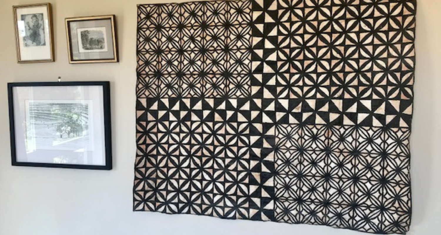 Wall with tapa cloth and framed photos. 