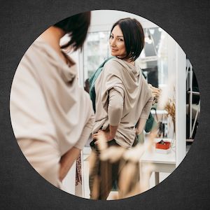 nicely dressed woman looking at herself in mirror