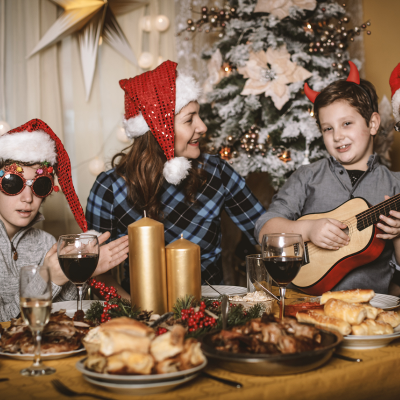 family at christmas dinner table sing with ukulele