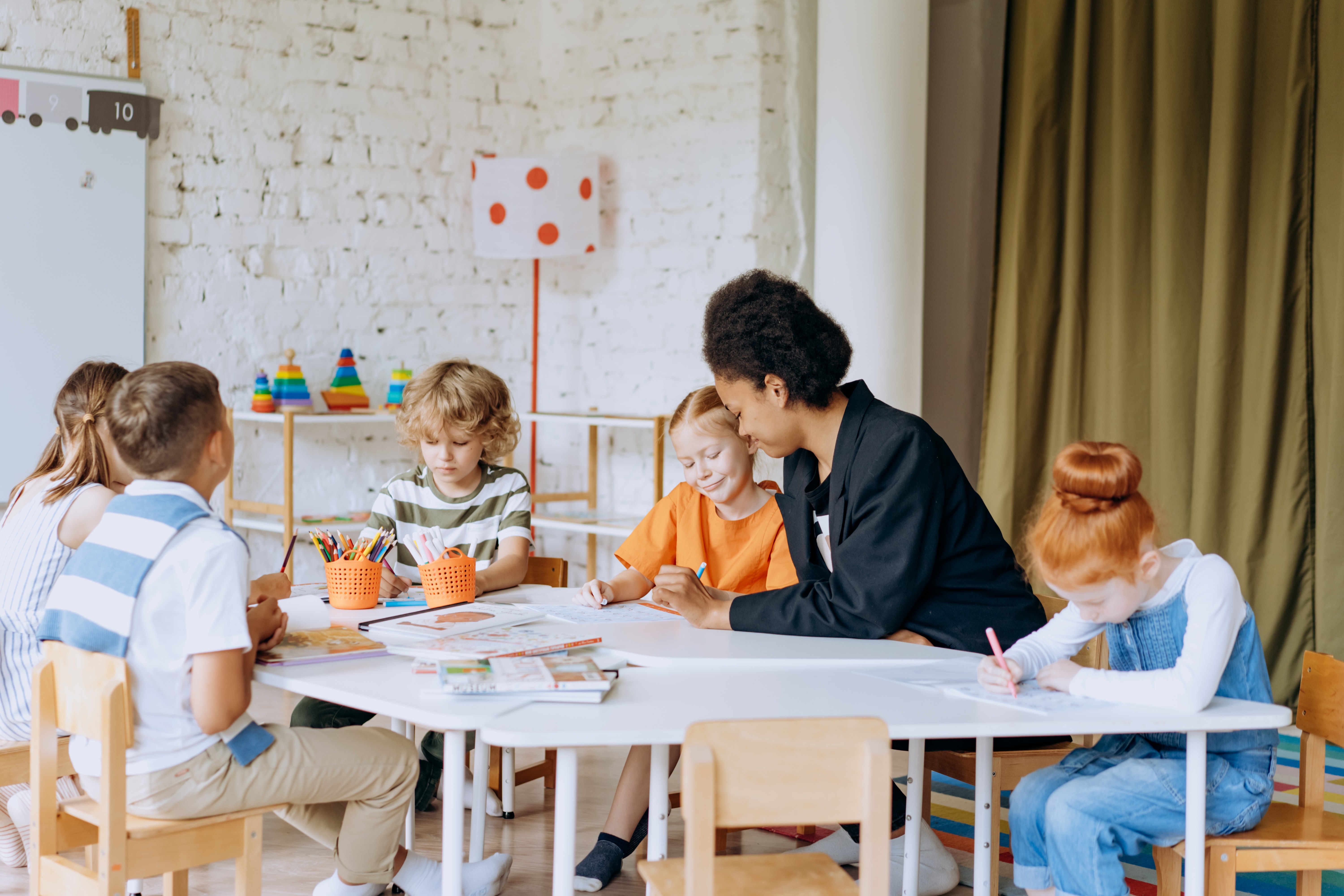 teacher sitting at tables with students working around her