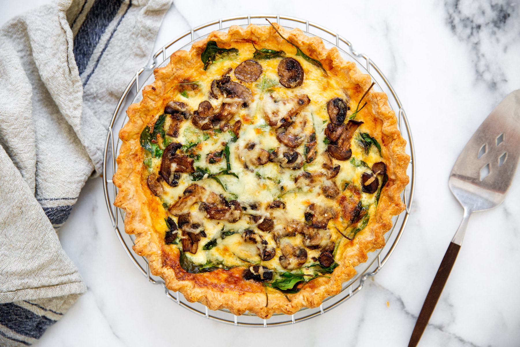 Spinach and mushroom quiche on a cooling rack.