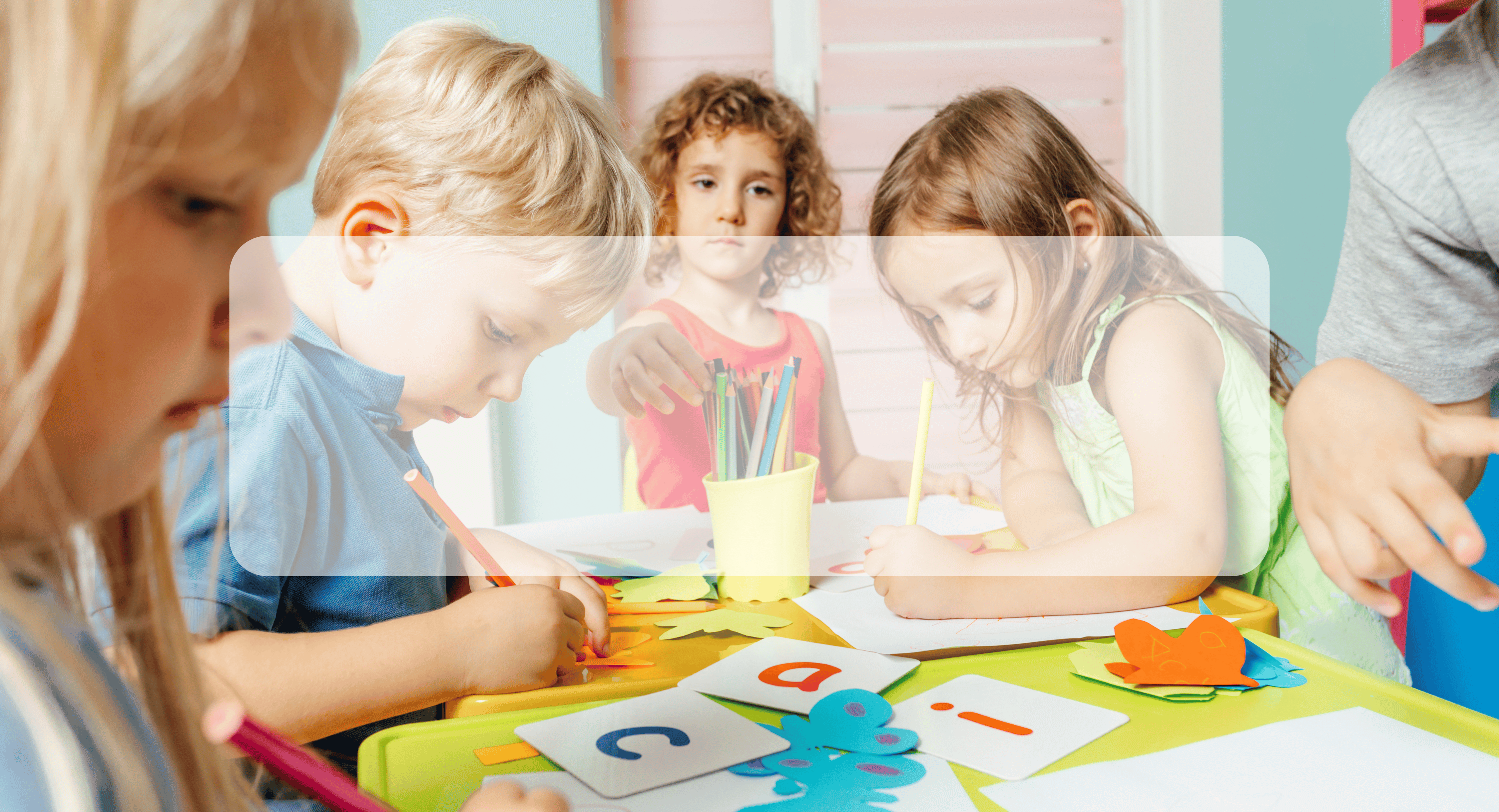 early childhood students sitting around a desk working on literacy skills