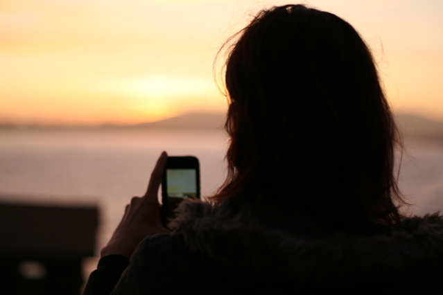 Woman with smartphone and sunrise in background