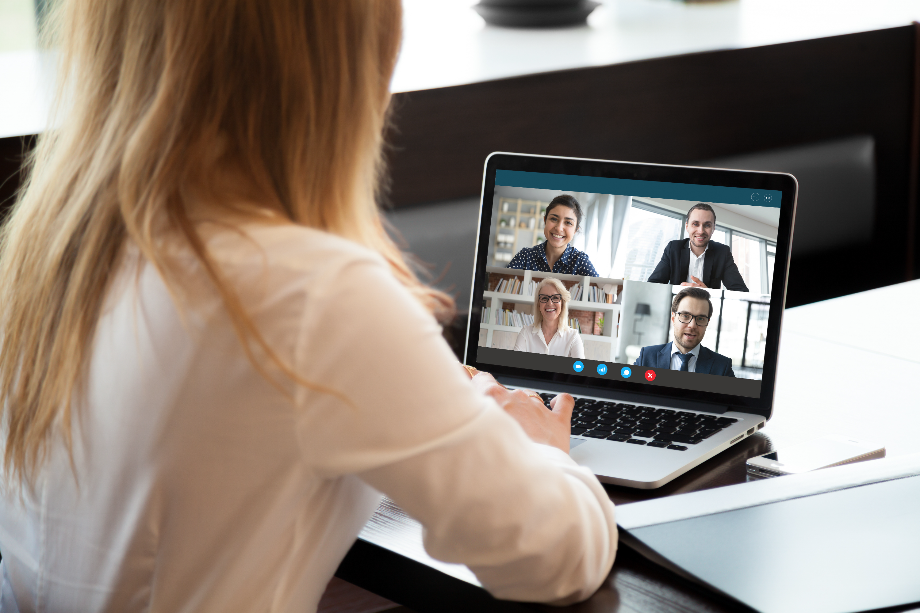 Woman in online meeting looking at laptop with 4 participants online