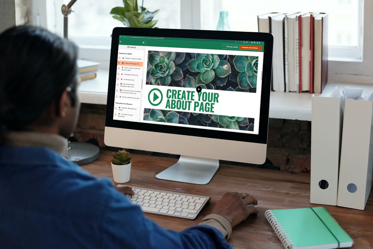 A man working on a desktop computer watching the create your about page video lesson for his personal website