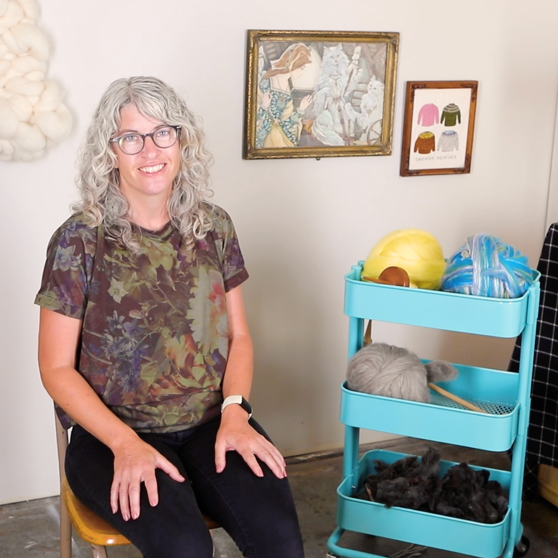 A photo of Jaime beside a cart of roving and spinning supplies