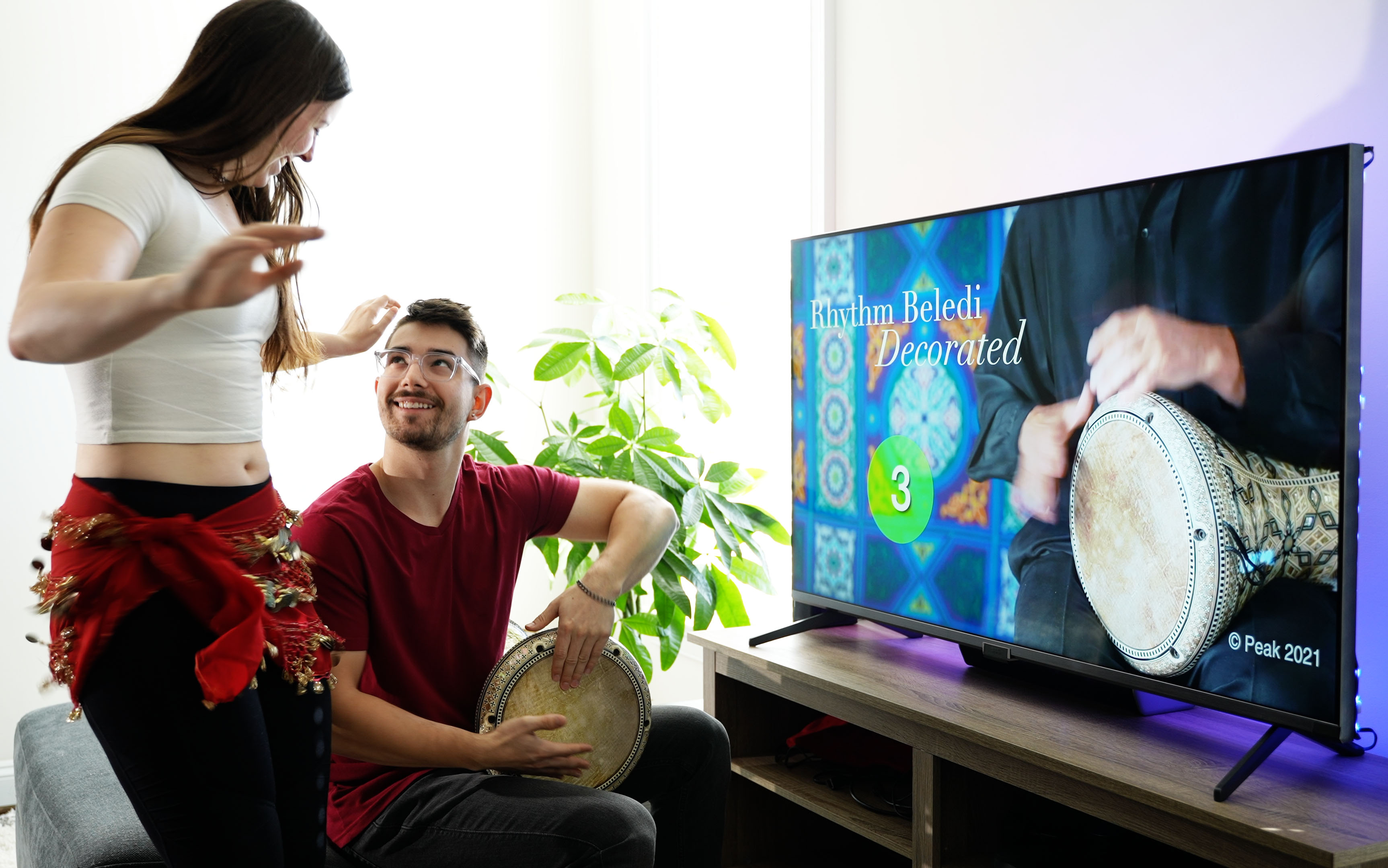 Belly dancer and drummer practicing in front of TV with online rhythm course