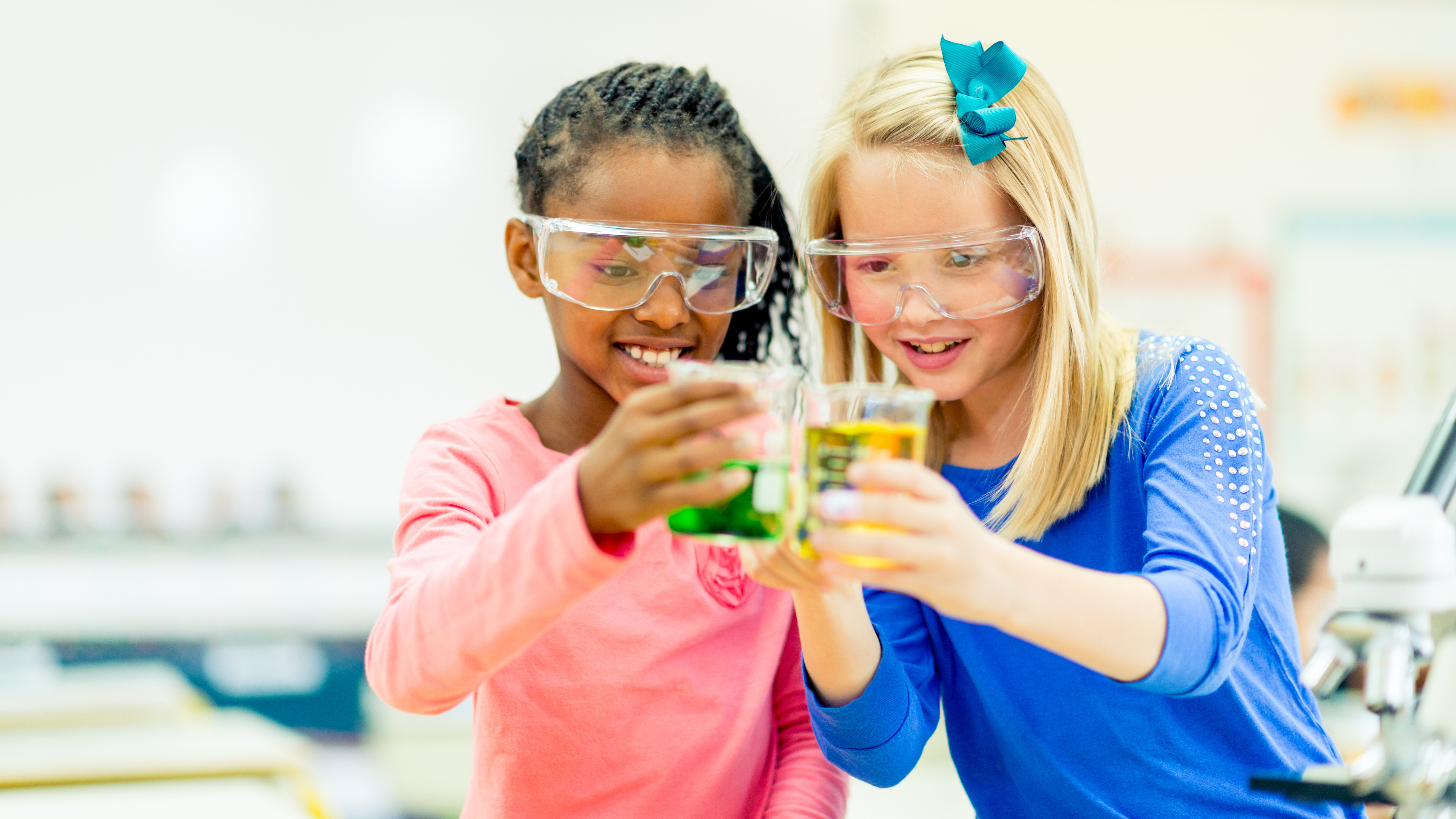 two girls observing liquids in beakers
