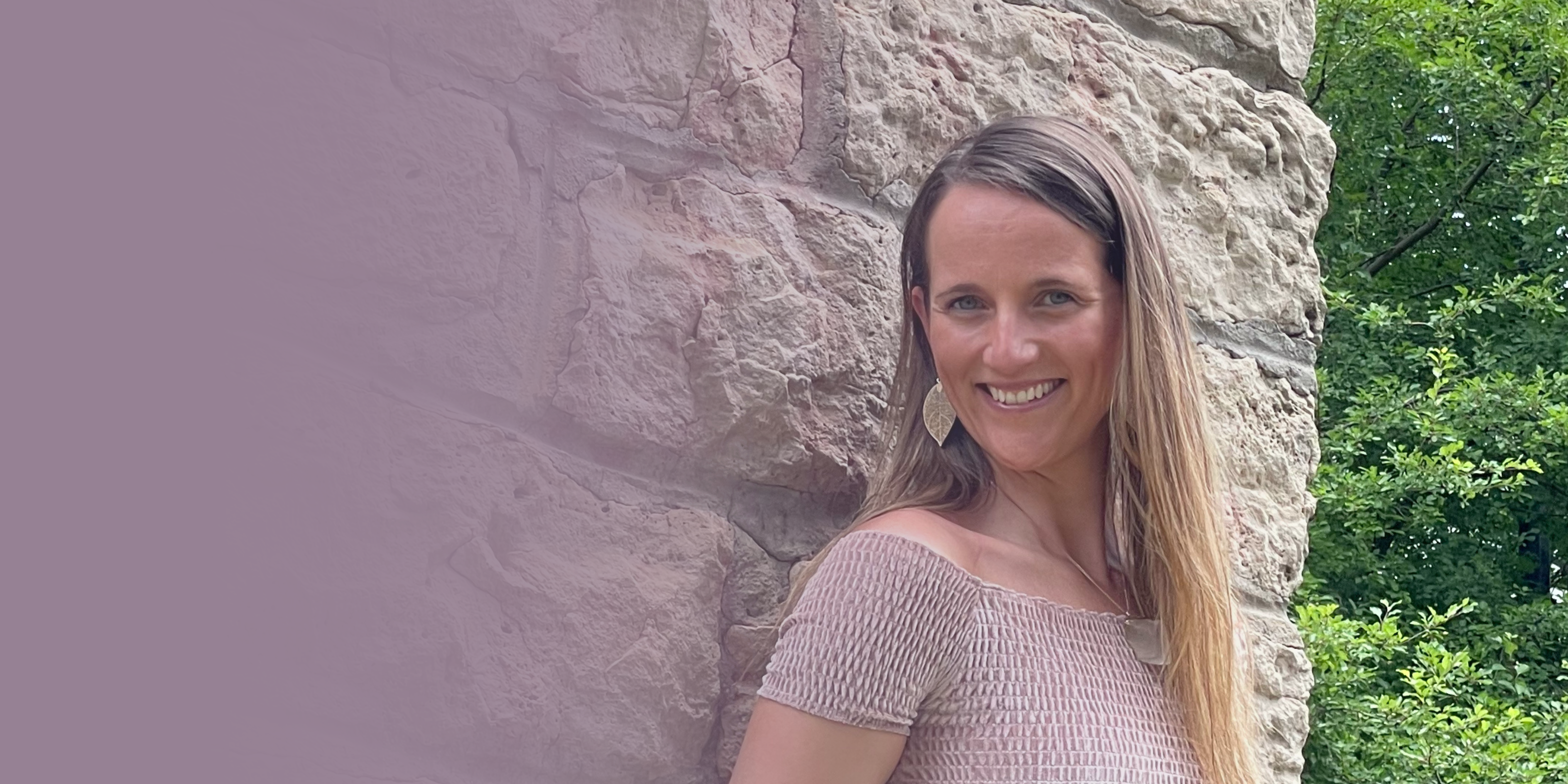 Intuitive Woman leaning against a stone wall,smiling, happy 