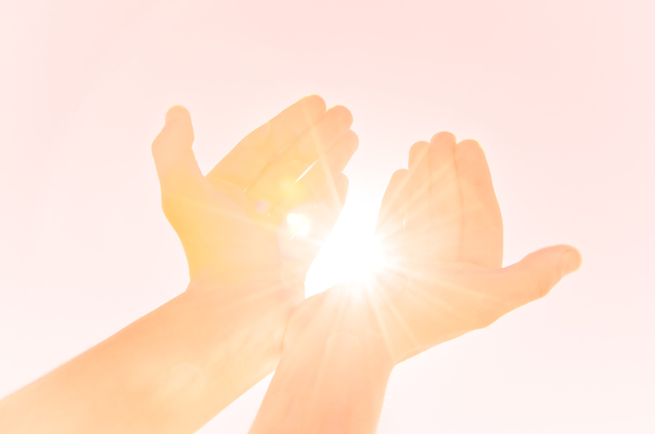 Two hands raised up towards the sun