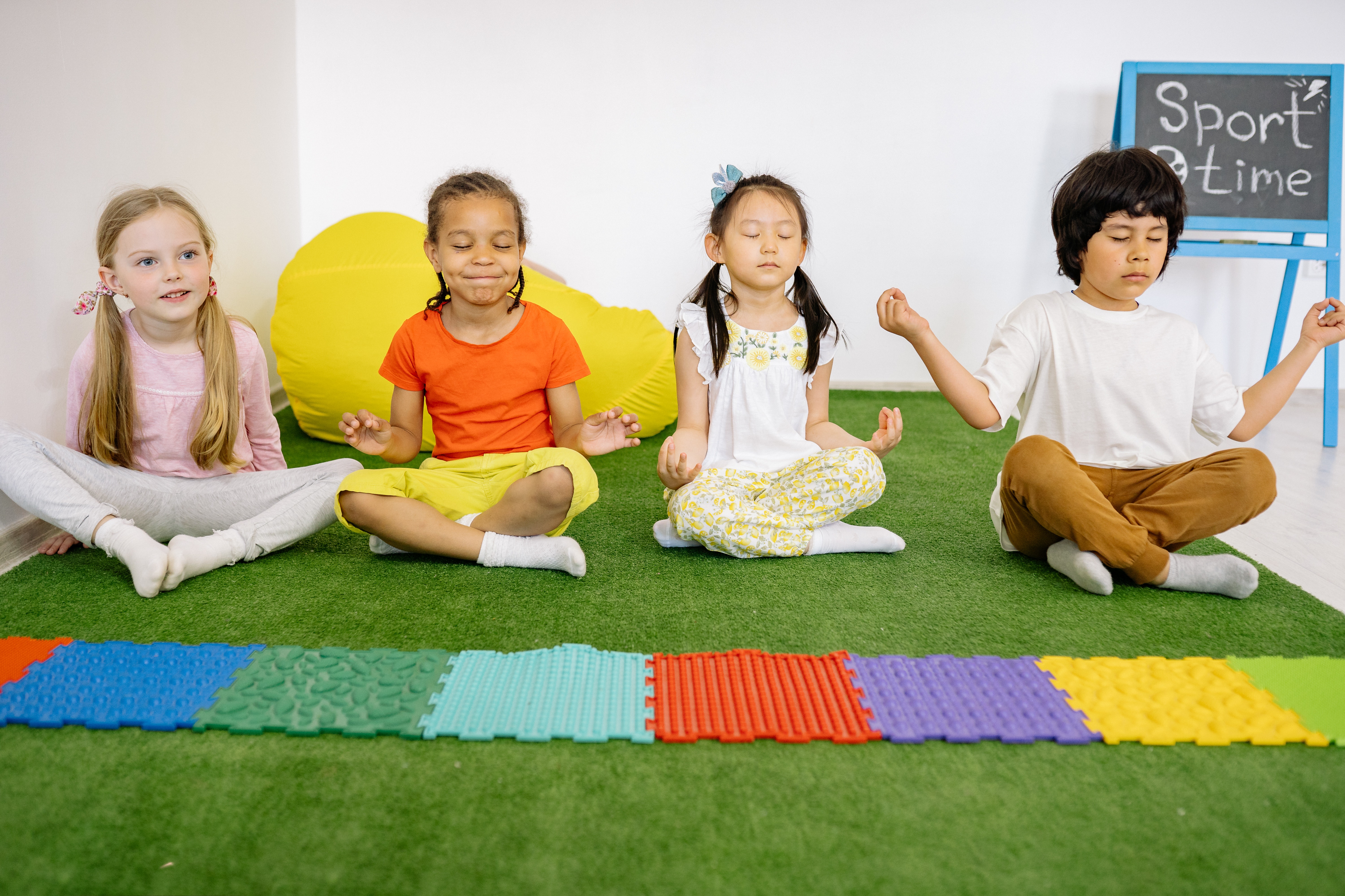 four kids sitting on the floor in a yoga pose