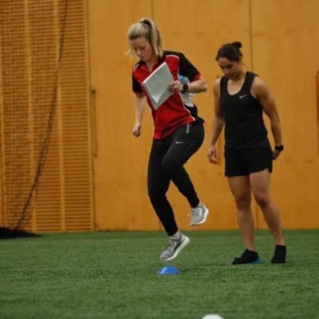 Physio helps young girl with ACL recovery in an indoor sporting field.