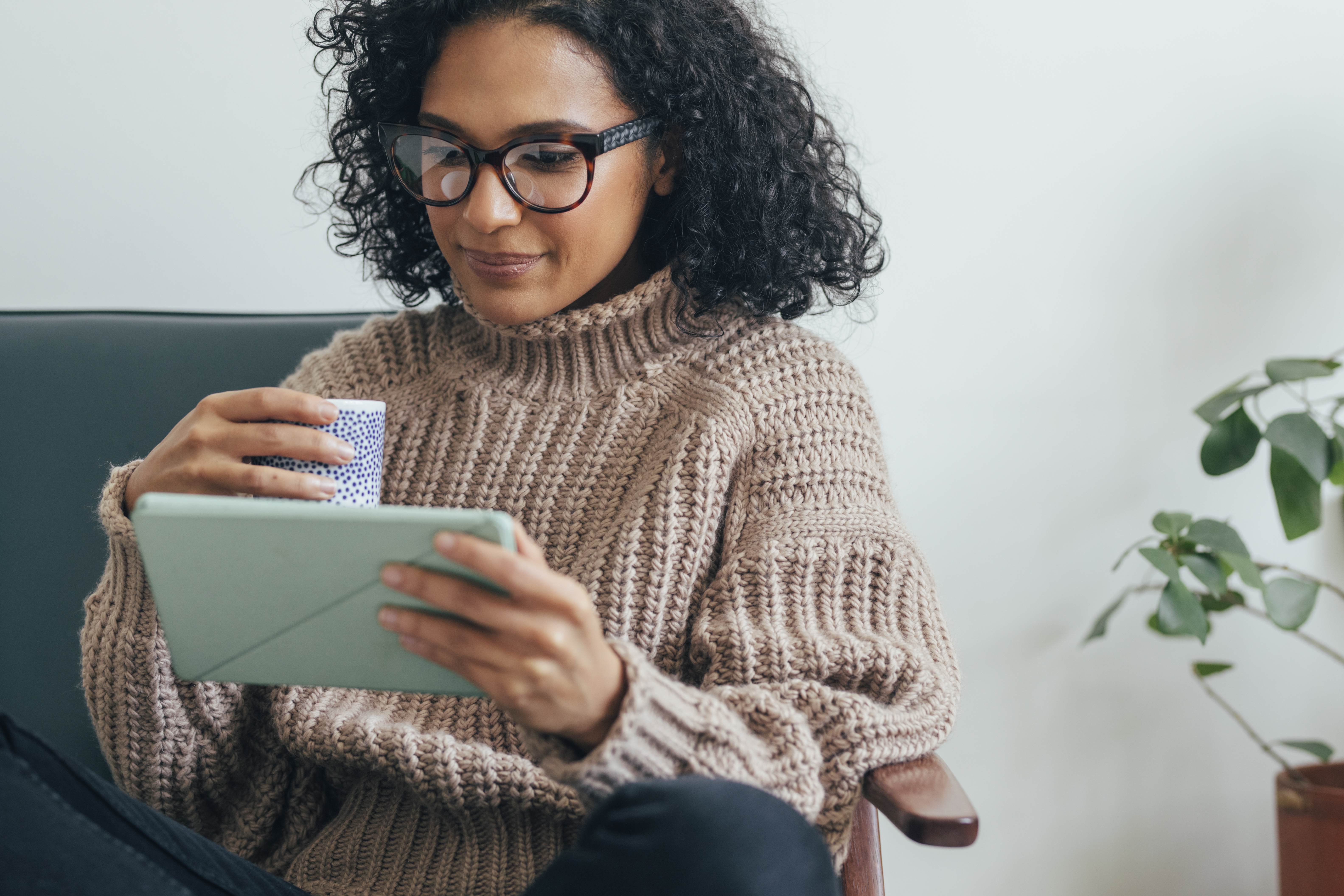 Young professional female drinking coffee while reading tablet.