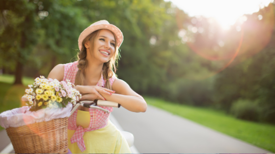 Woman in summer clothes on a bicycle with a basket of flowers 