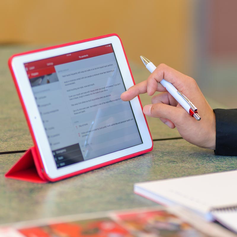 Close-up of a tablet screen with a Red Cross webpage and a person looking at the content.