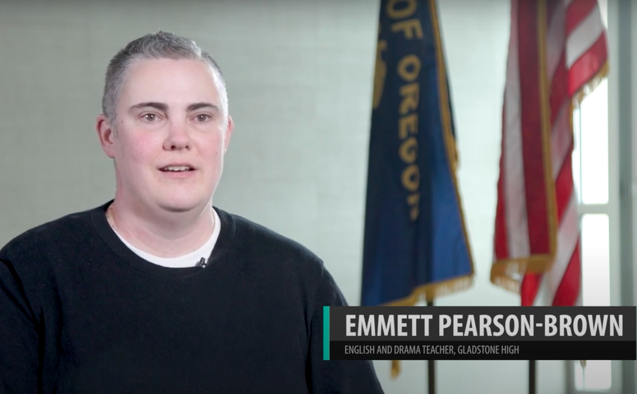 Educator being interviewed with an Oregon and an American flag in background