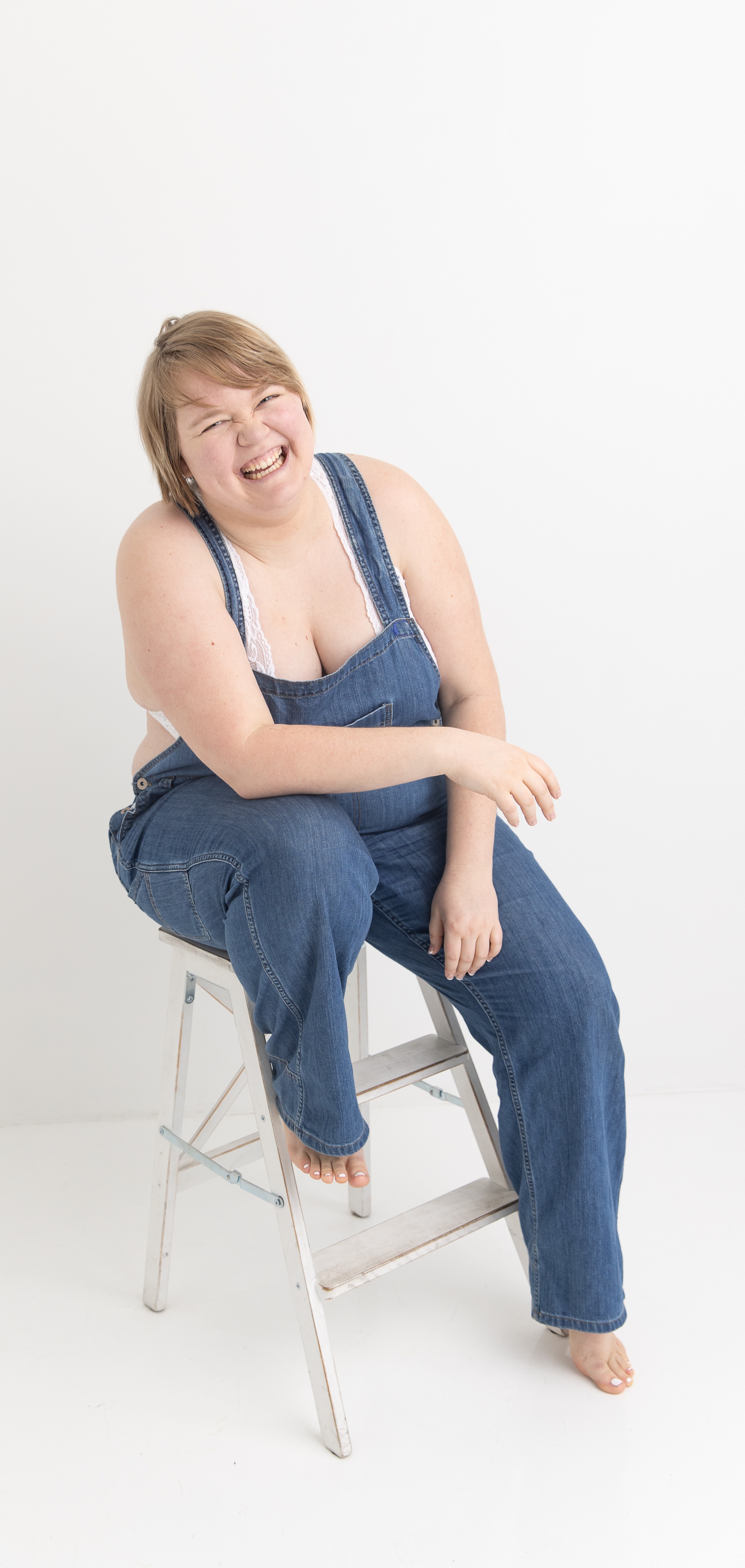 Kami wearing blue overalls sitting on a step stool