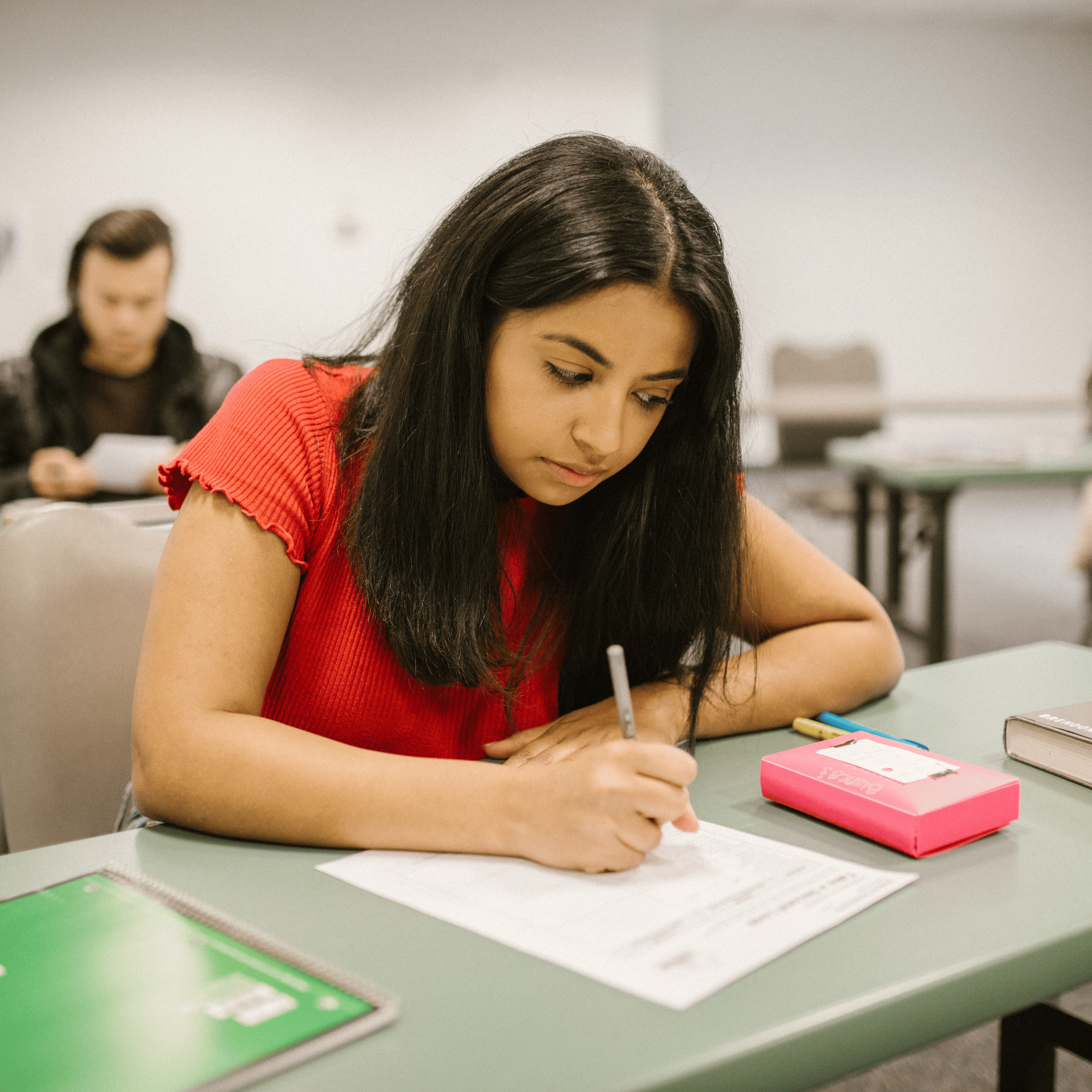 student writing with pen and paper on desk