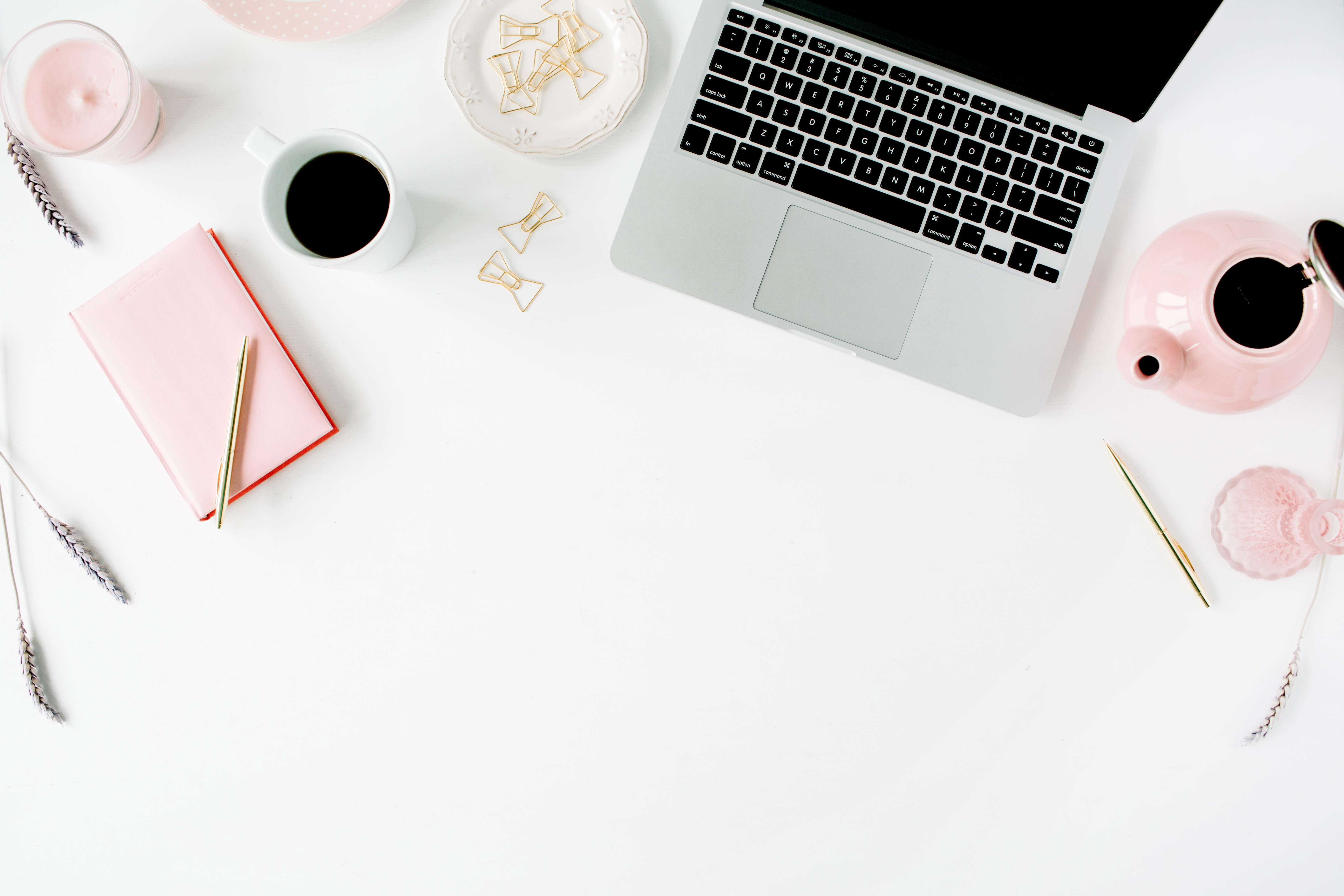 laptop and coffee on desk with pink supplies