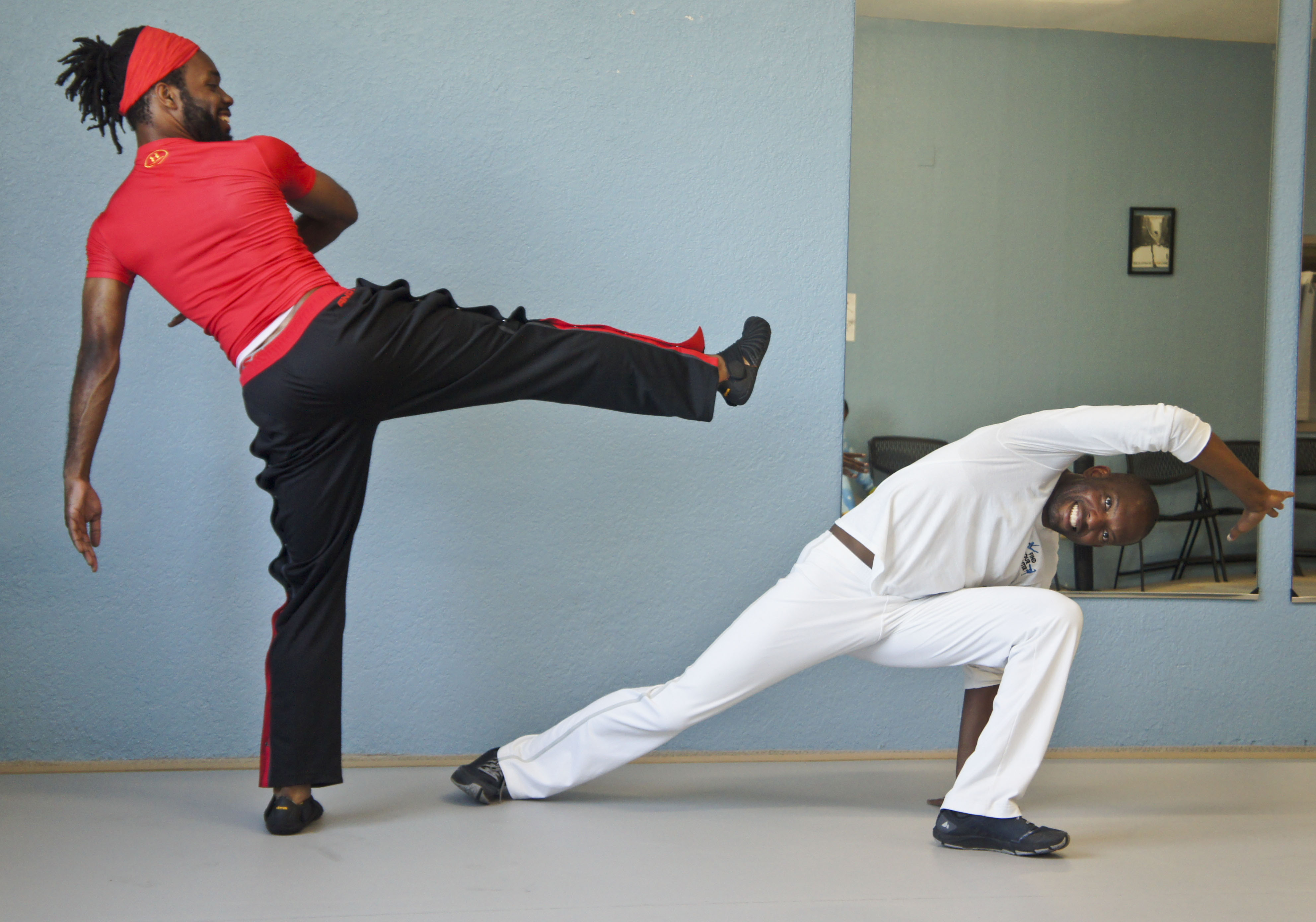 Instructor DeShawn &quot;Quiabo&quot; Robins poses in a side escape movement while his student poses in a kick toward him