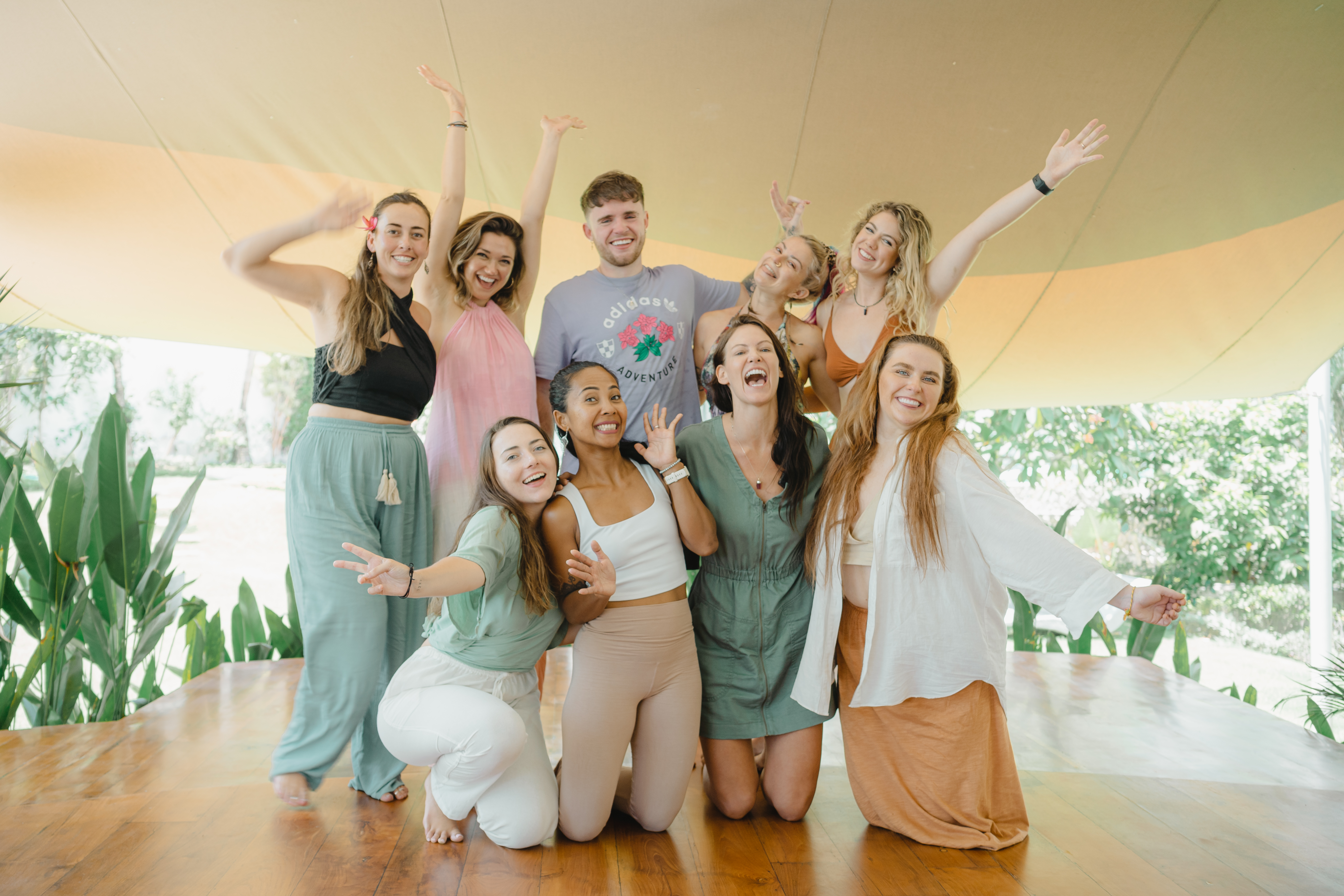 A group of people cheering. They have just completed a meditation and breathwork class. They are feeling relieved and happy. They are in an outdoor yoga shala. They feel very mindful.