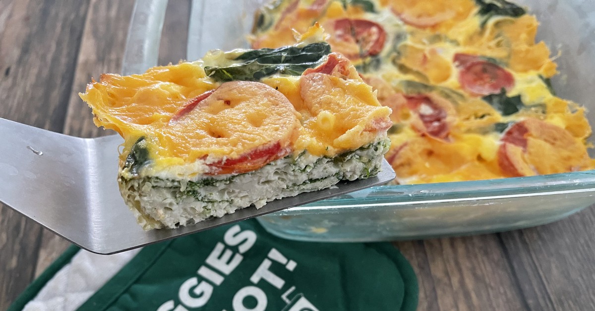 egg white and vegetable bake slice on a spatula over table with pan with hot pad