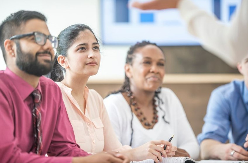 four people looking attentively at a trainer