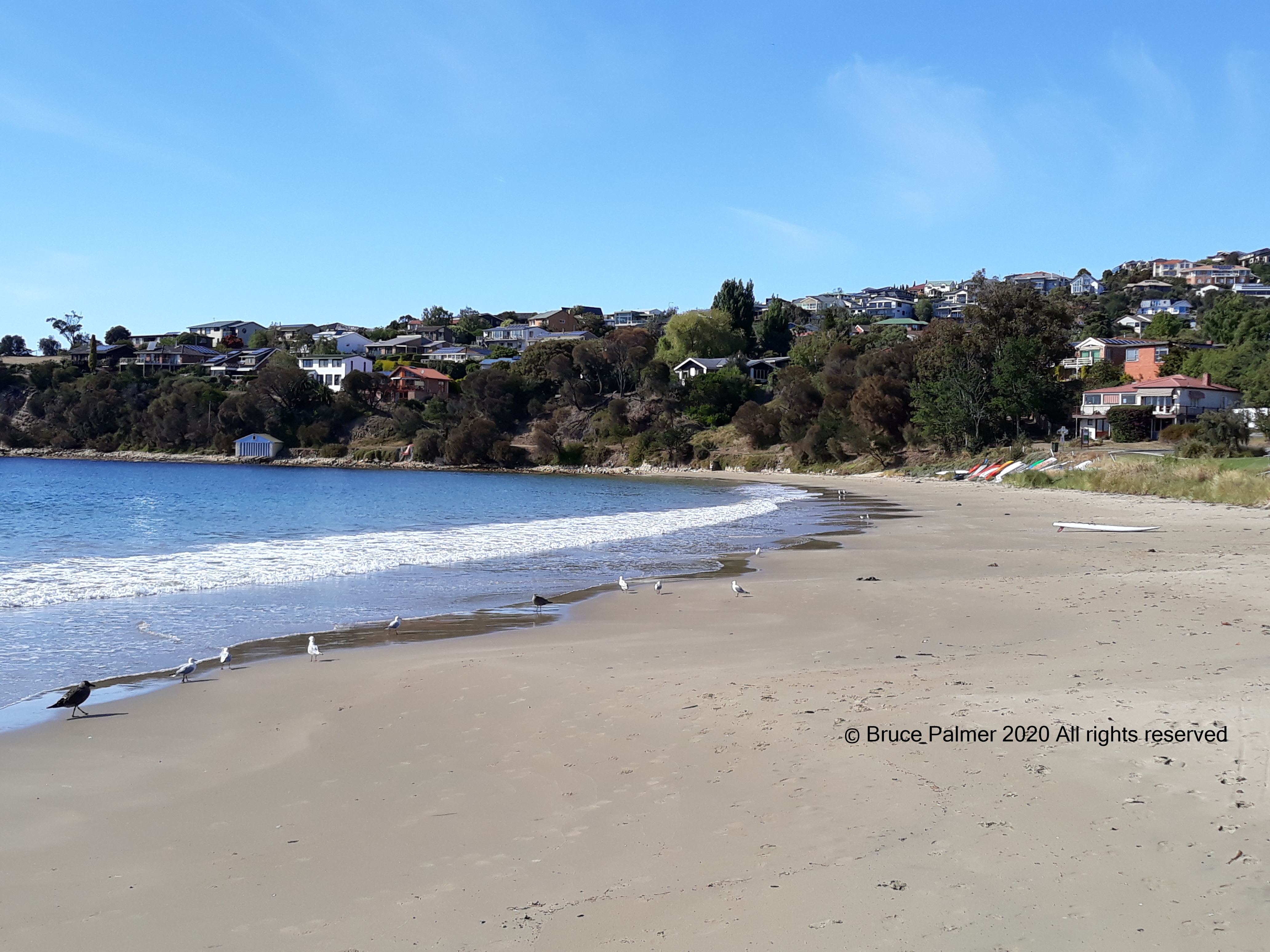 Stress Control Made Easy. Relaxed beach with ripple waves and a blue and white boathouse in the distance