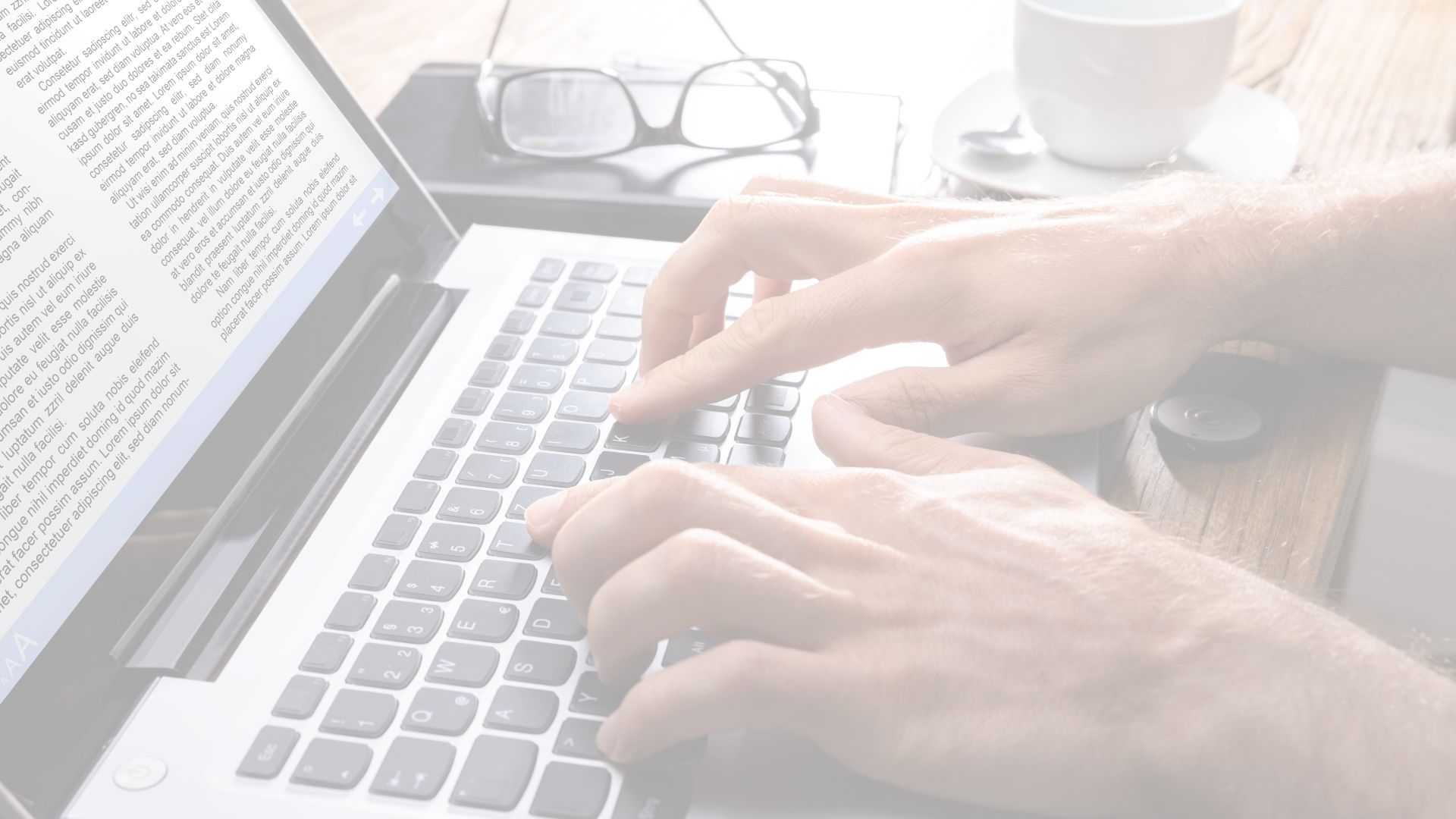 A person typing on a laptop with a journal article on the screen.