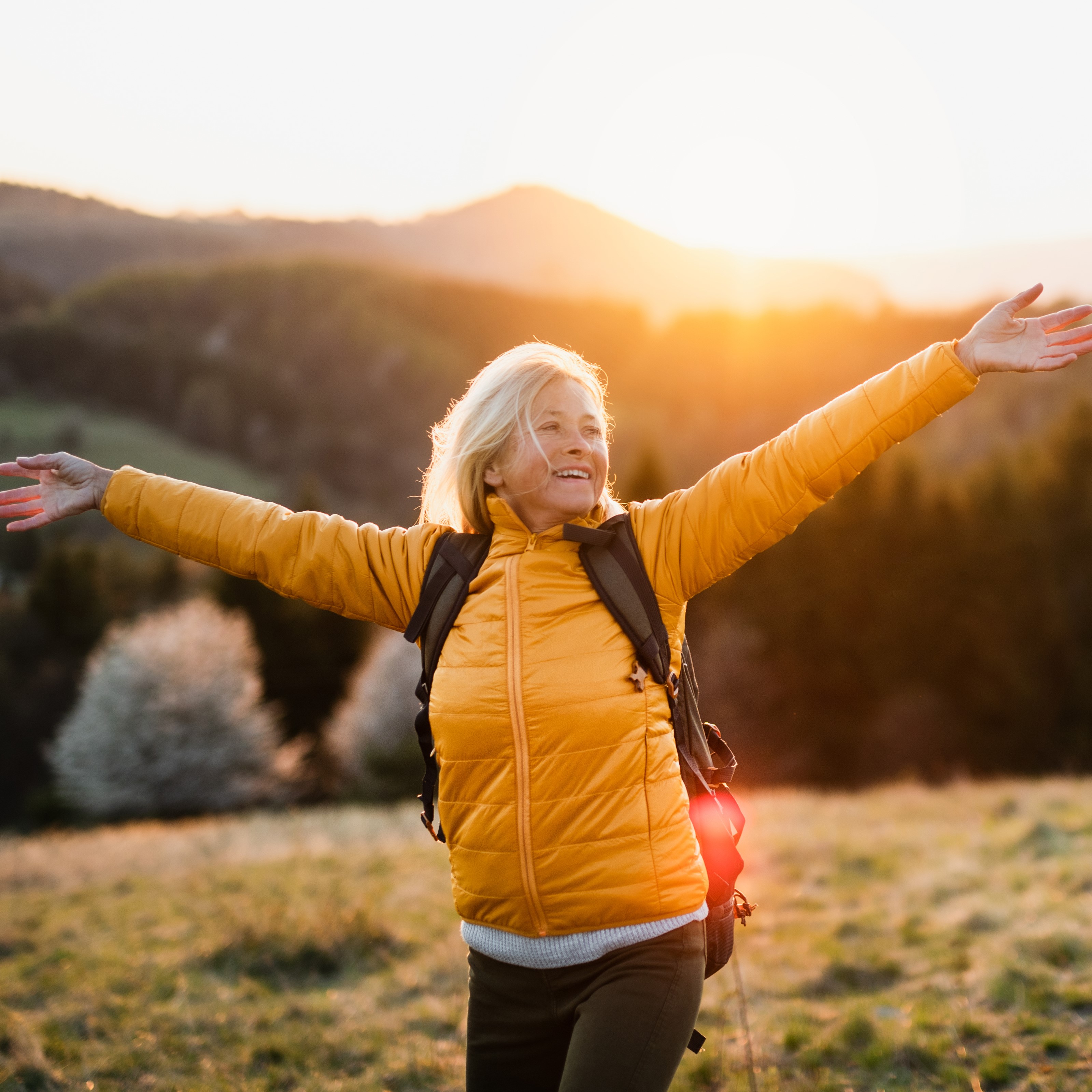 Retired woman on a mountain with her arms open