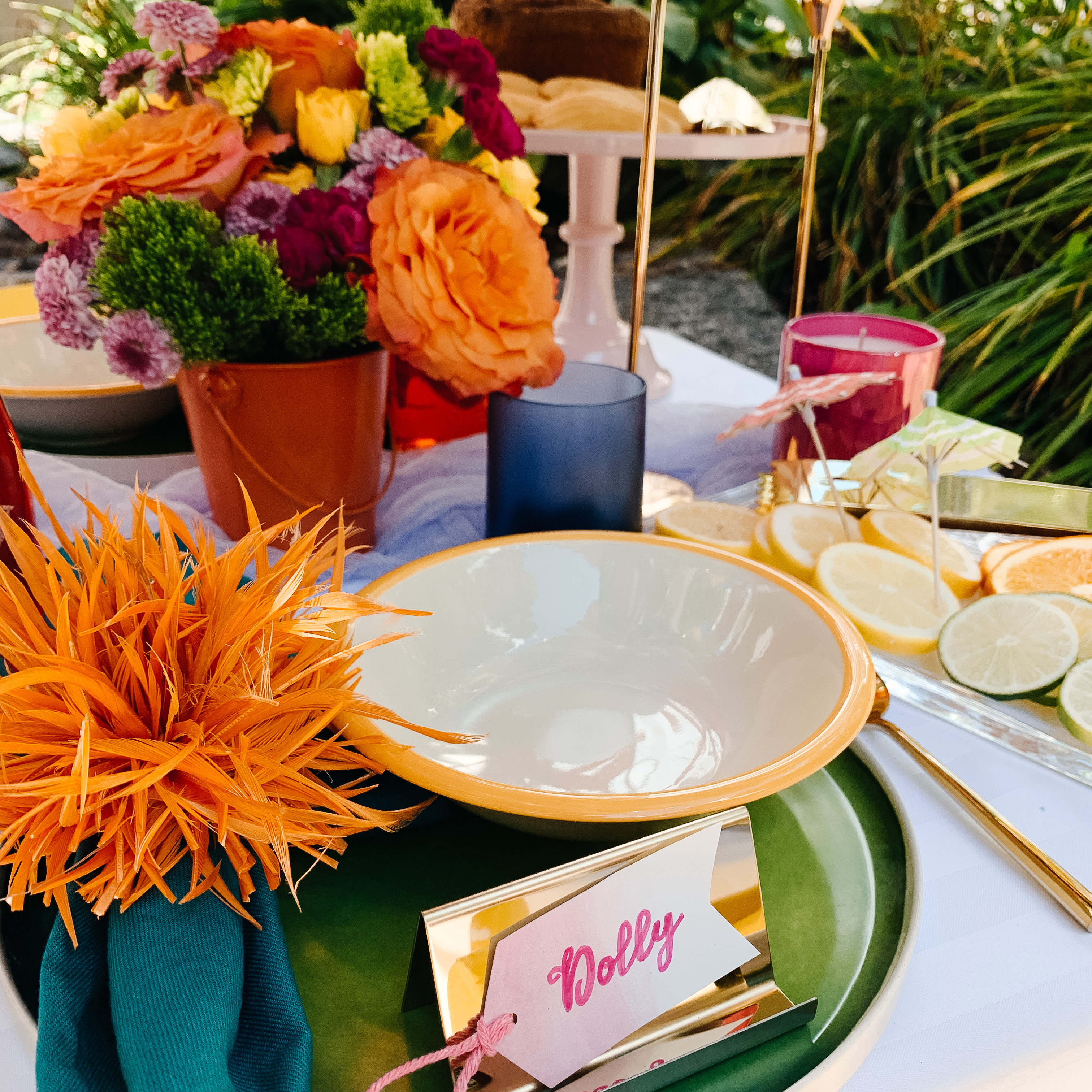 Spring tablescape with bright flowers, candlesticks, white bowl, and green plate