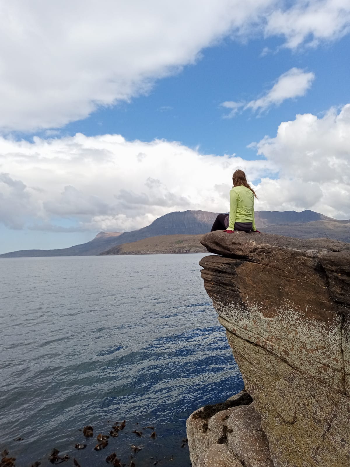 English Language Coach for non-native Teachers of English, sitting on a rock, looking out at the Summer Isles