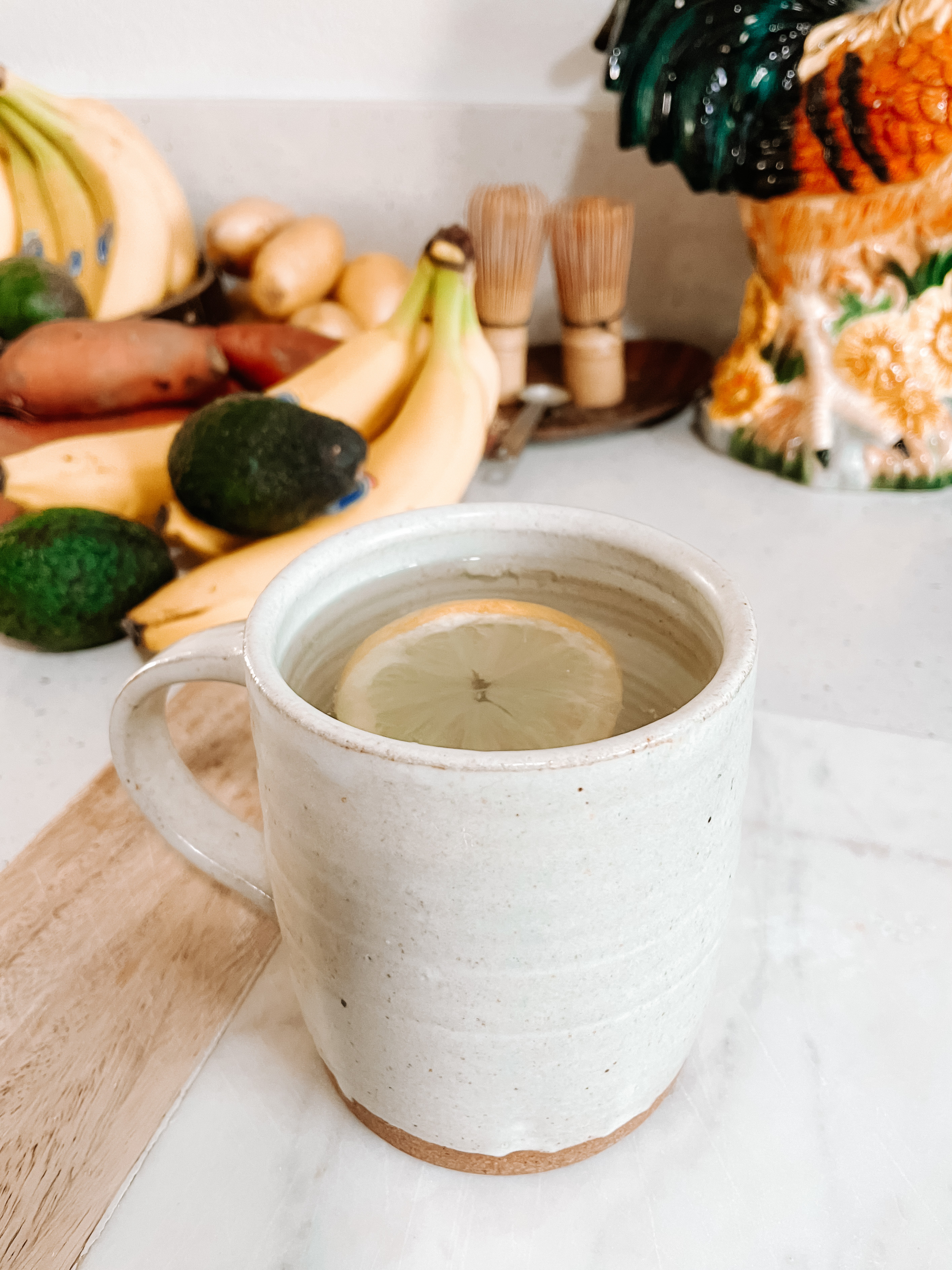 Salty lemon water in front of basket of fruit and vegetables.