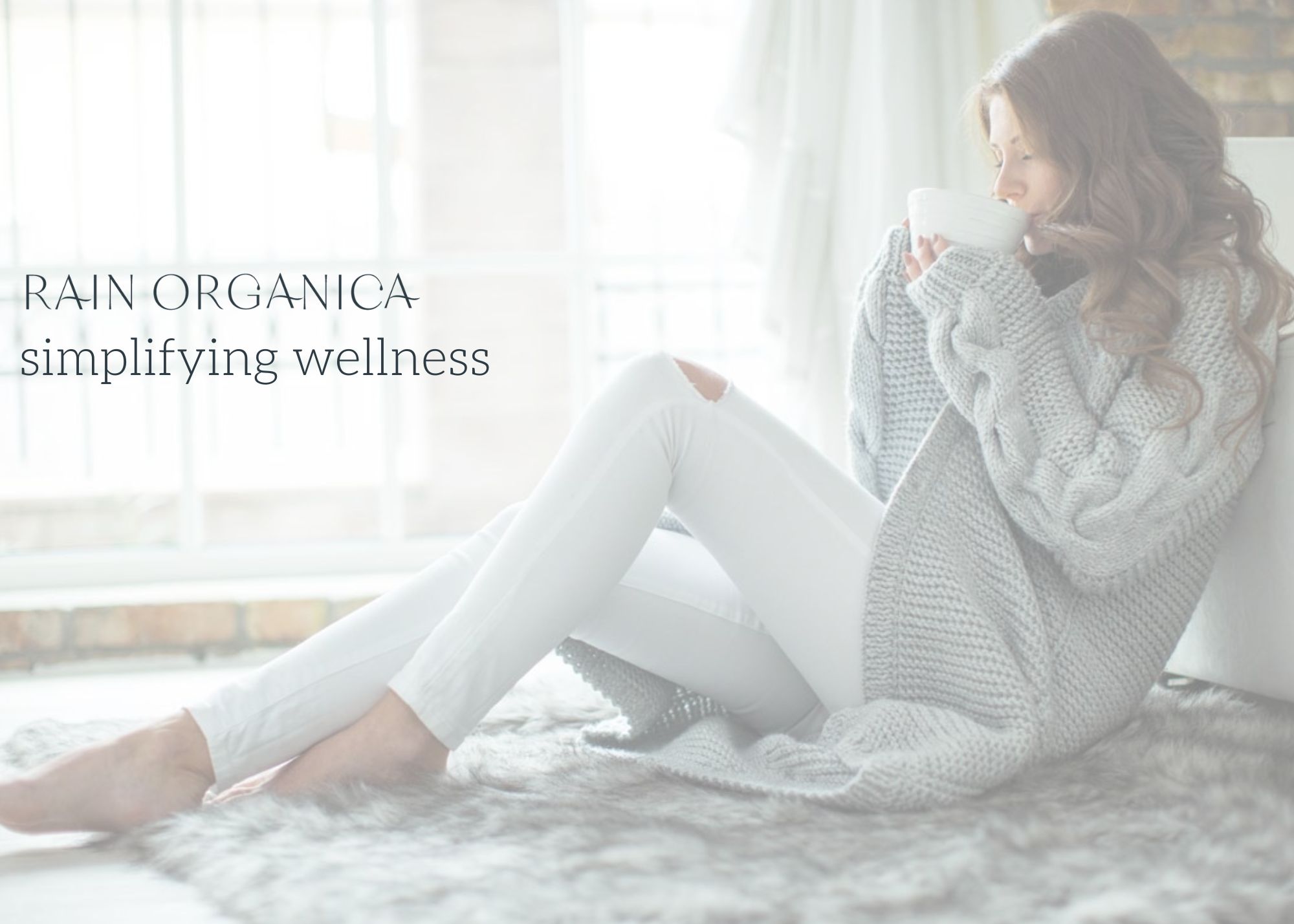 woman drinking tea in a cozy sweater on a cozy rug next to a bright window