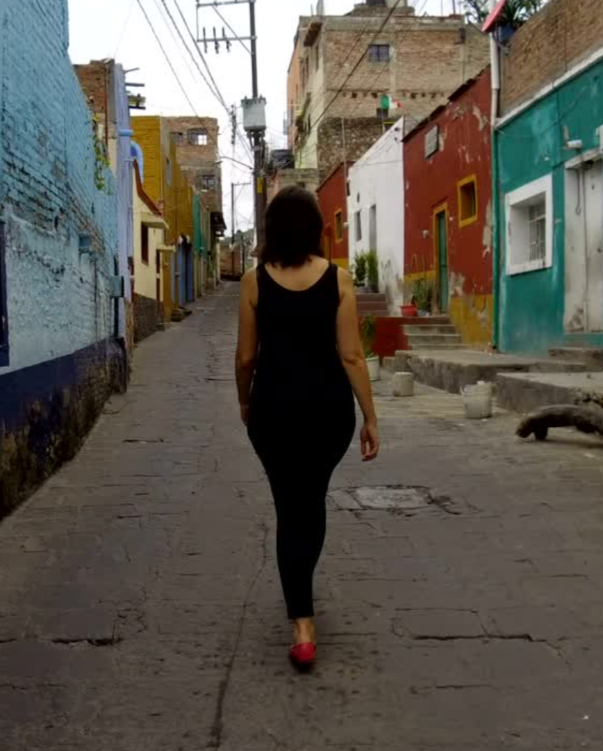 Mujer caminando por una calle entre casa de diferentes colores